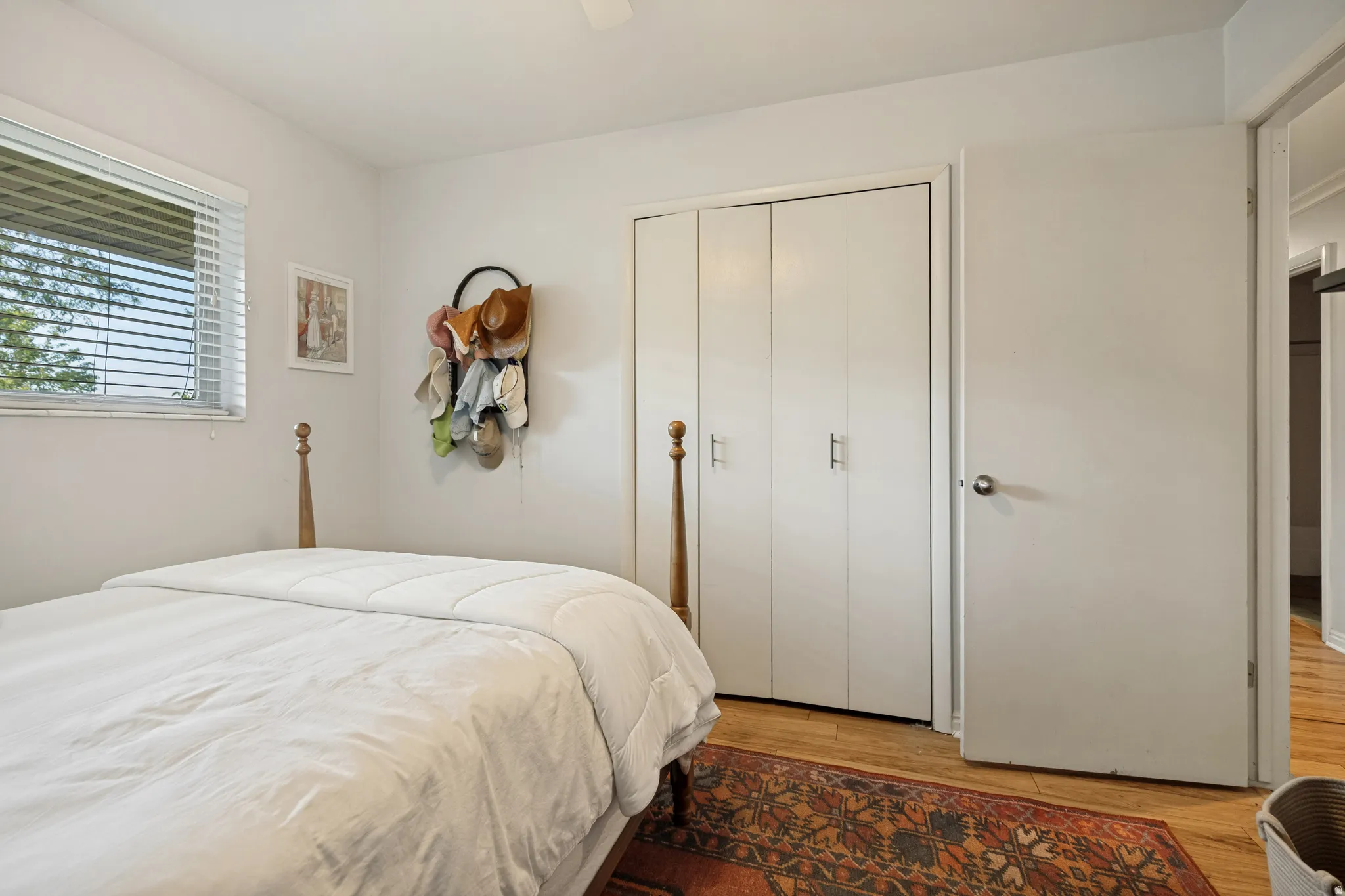 Bright secondary bedroom featuring hardwood flooring, an ornamental brass bed frame, and generous natural light from the window