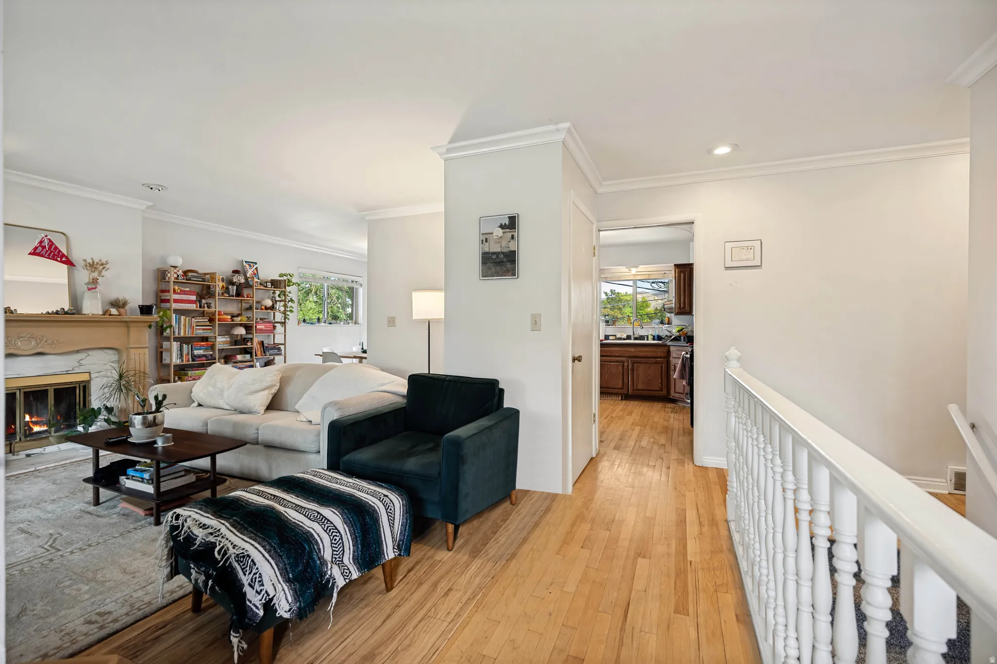 Living area featuring a stone-surround fireplace with a wood mantel, crown molding, wood-finish flooring, and recessed lighting