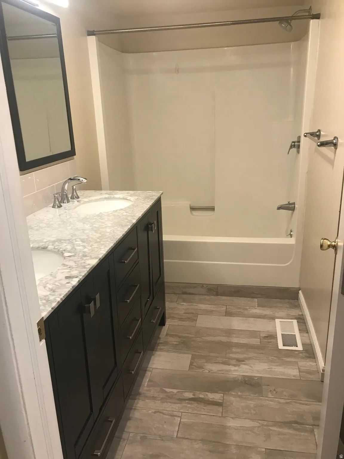 Dual-sink vanity with a light-toned countertop, dark cabinetry, and brushed nickel hardware