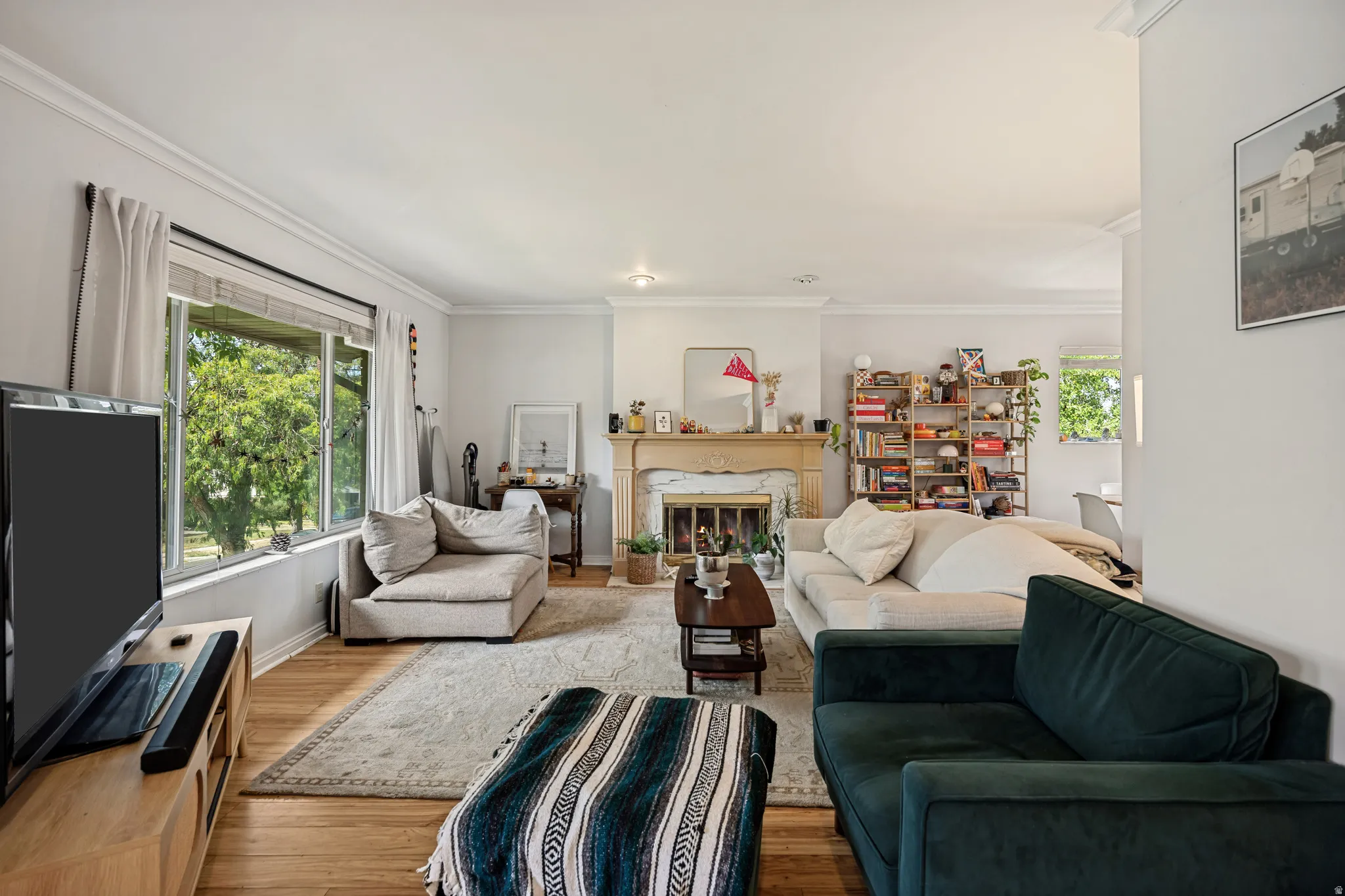 Living area with wood-finish flooring, crown molding, and large windows