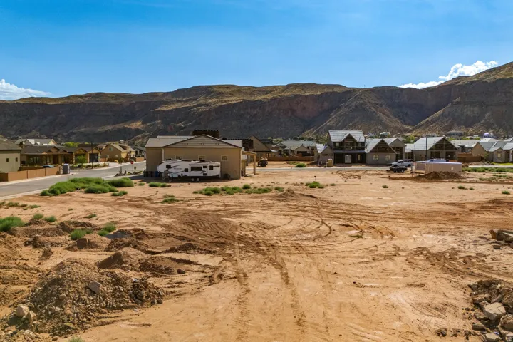 Expansive land parcel with surrounding residential development and a dramatic mountain backdrop