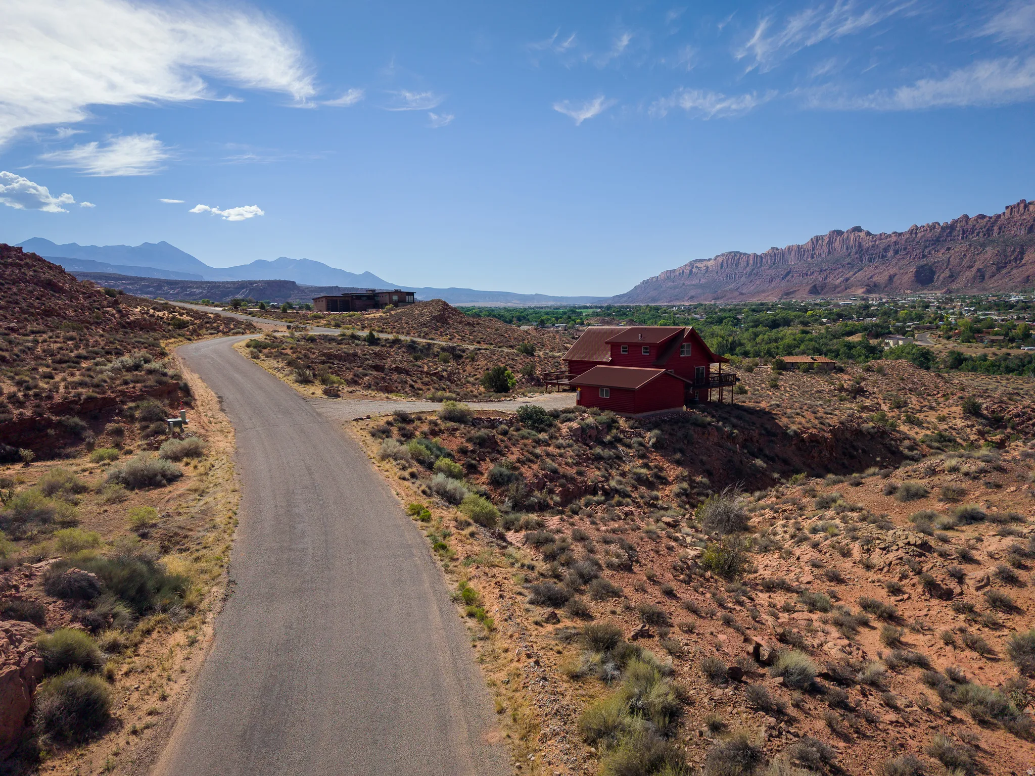 Red multi-story residence with a pitched roof, situated on a terraced desert landscape