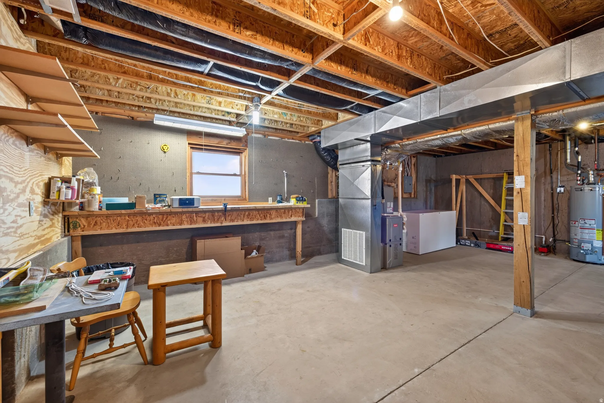 Concrete flooring, exposed ceiling joists, and a perimeter workbench with shelving