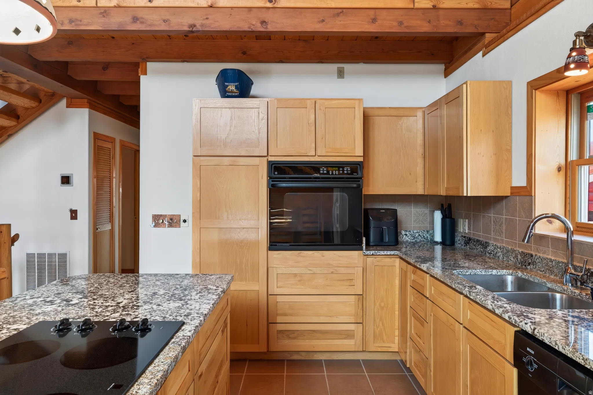 Kitchen featuring light wood cabinetry, stone countertops, a double basin sink, and an integrated wall oven