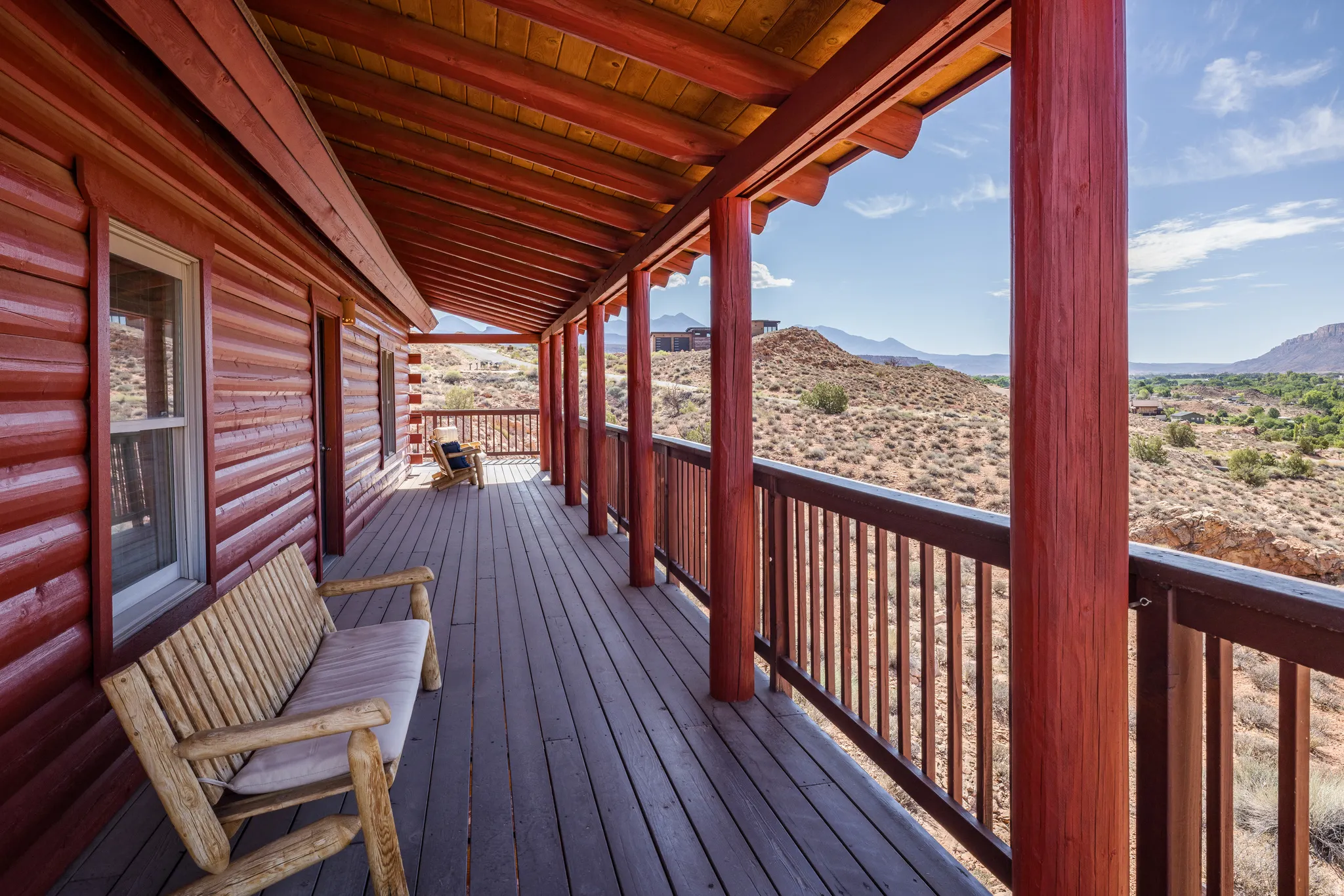 Expansive log cabin exterior featuring a covered porch, wood-finish decking, and robust structural columns