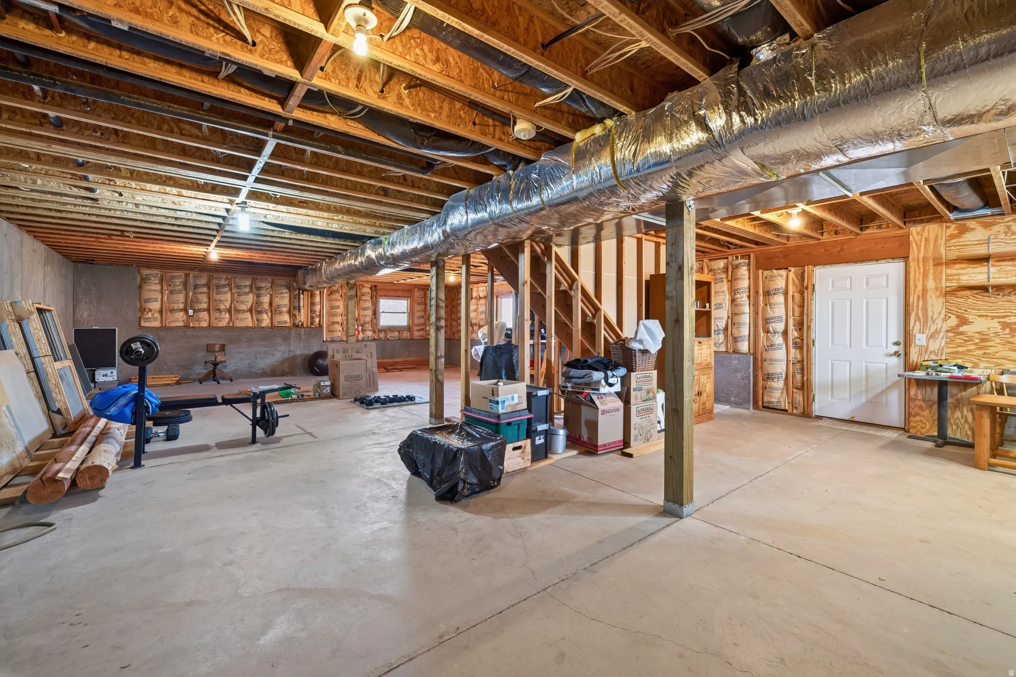 Unfinished basement featuring exposed wood joists, concrete flooring, and visible ductwork