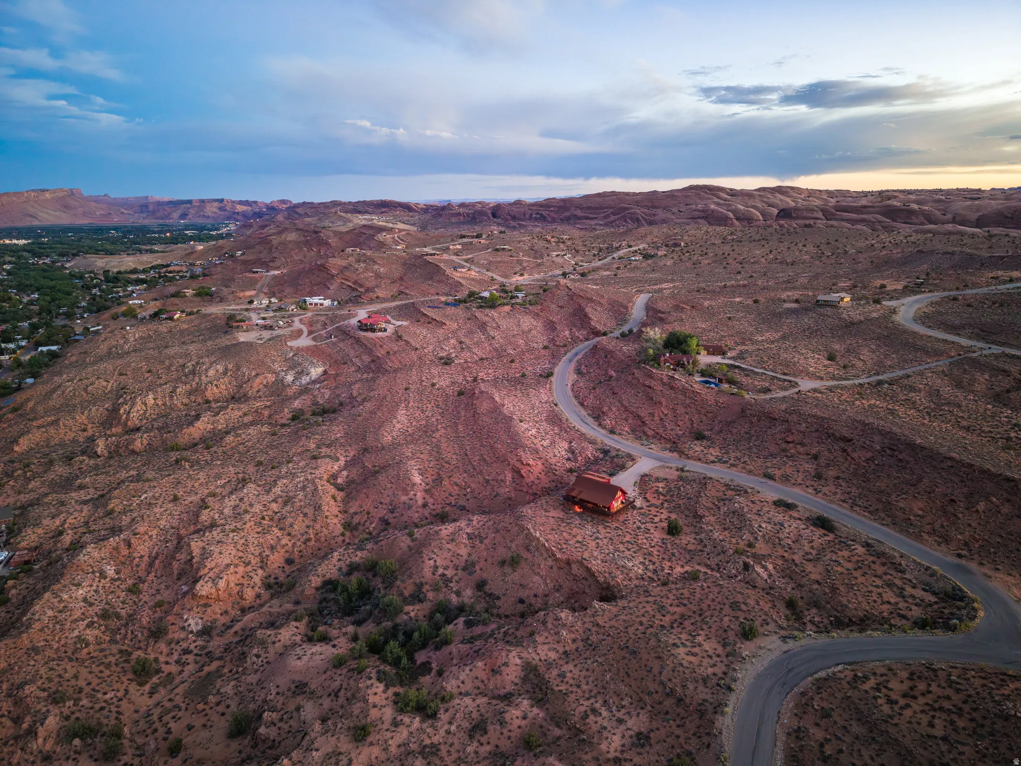 Expansive desert landscape with winding roads and distant structures, featuring varied topography and natural rock formations
