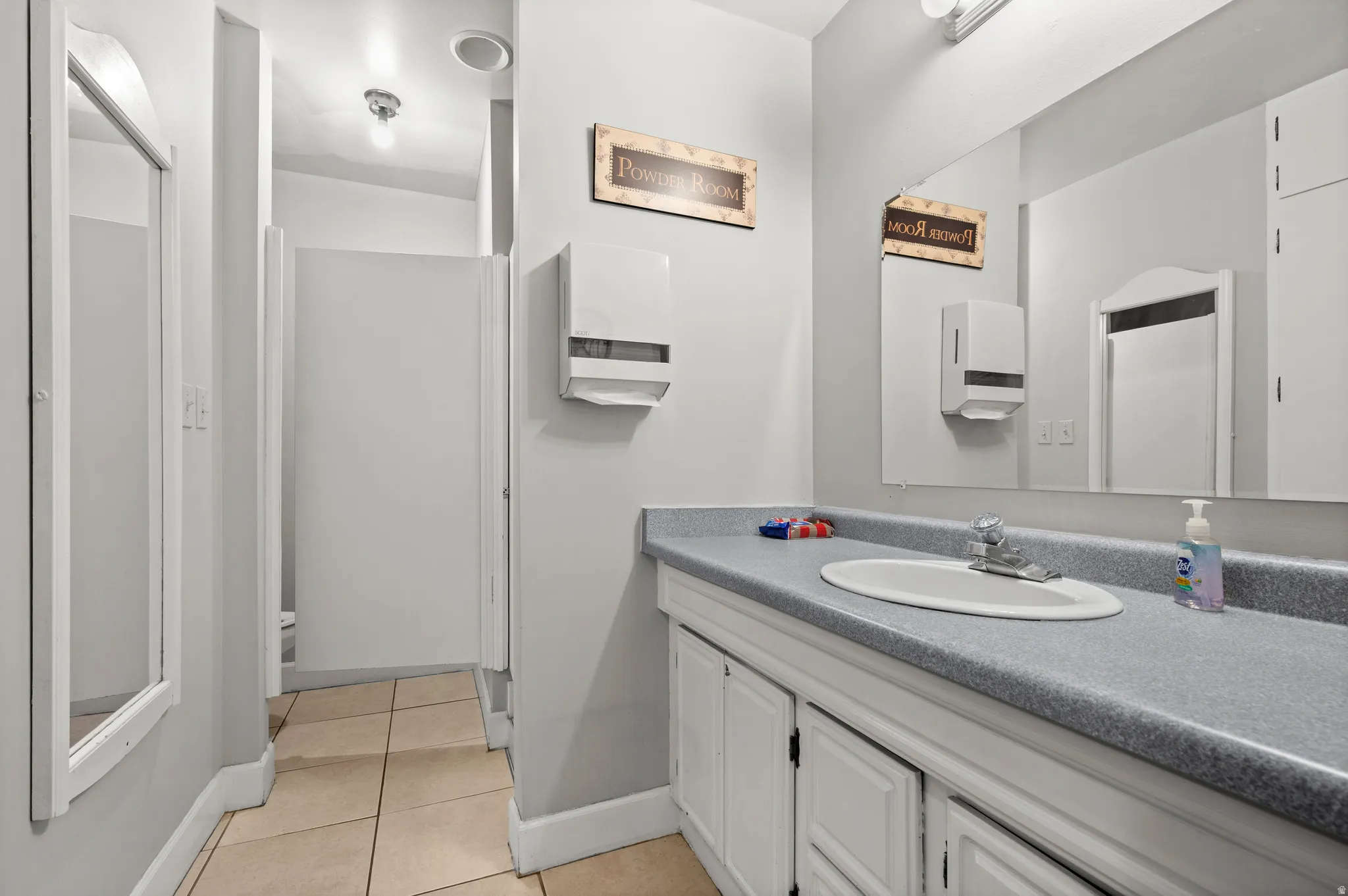 Expansive vanity with an integrated oval sink, laminate countertop, and built-in white cabinetry
