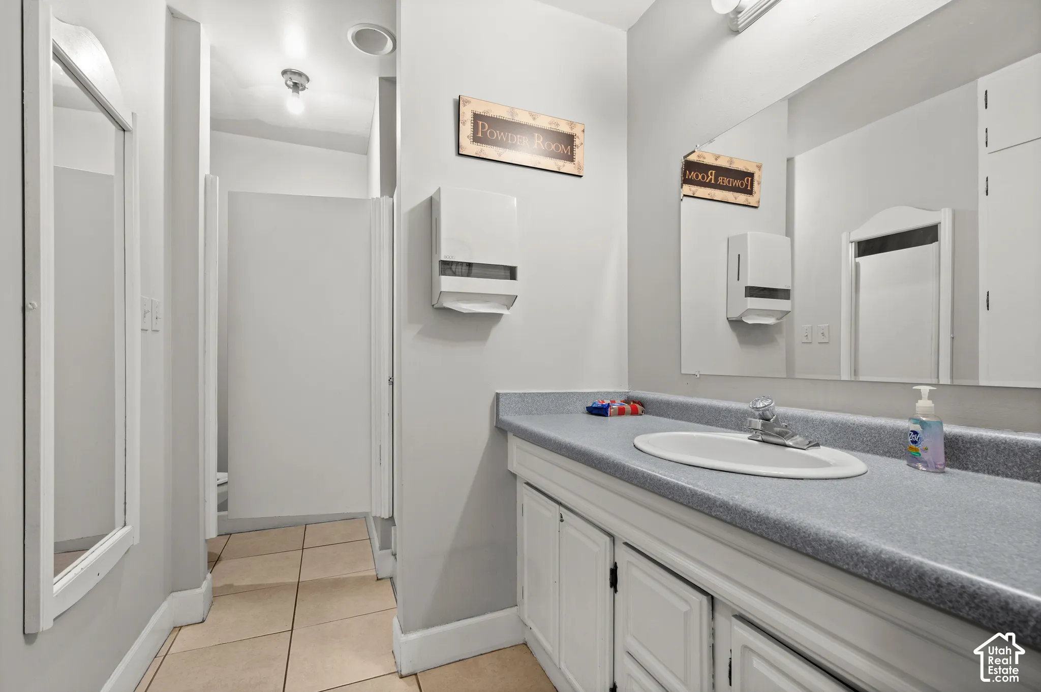 Expansive vanity with an integrated oval sink, laminate countertop, and built-in white cabinetry