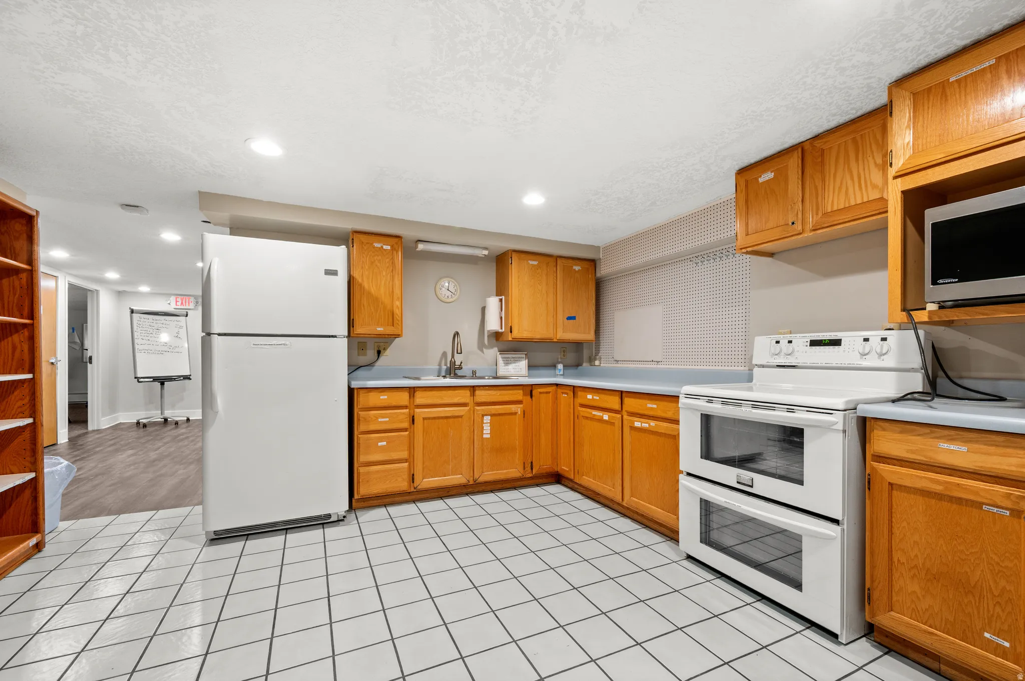 Kitchen featuring white square tile flooring, wood-finish cabinetry, and light-toned countertops