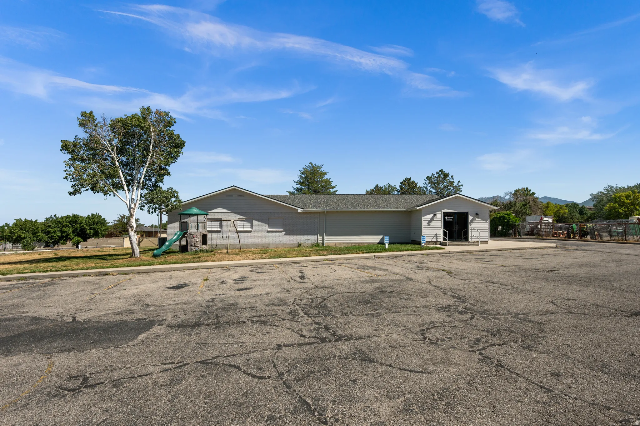 Exterior building with light gray siding, dark shingle roof, and a prominent entry
