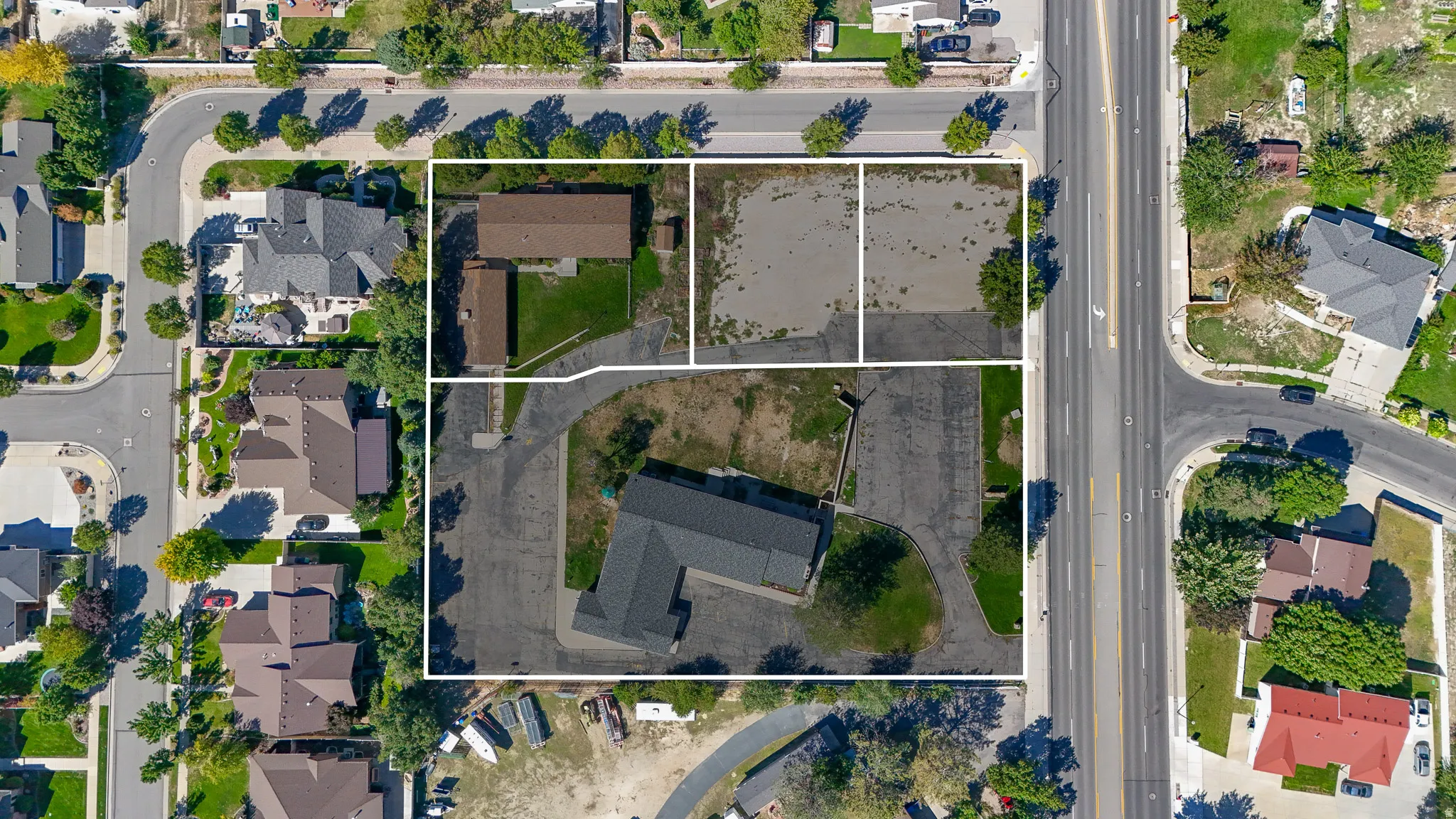 Aerial perspective showcasing multiple parcels, including two developed properties with buildings and two undeveloped land sections