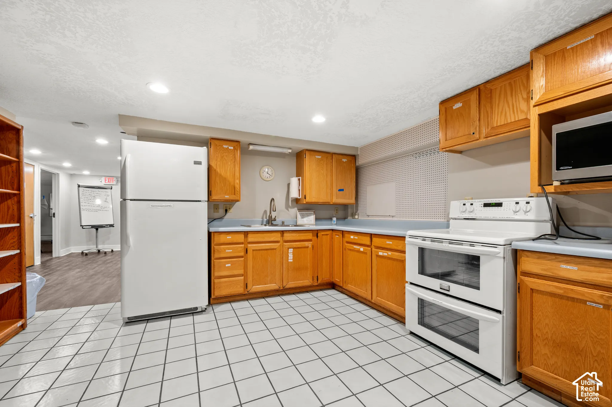 Kitchen featuring white square tile flooring, wood-finish cabinetry, and light-toned countertops