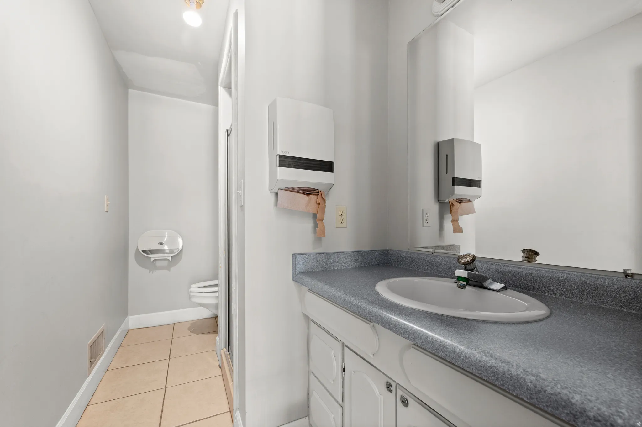 Vanity with an integrated sink, mirror, tiled flooring, and a light fixture
