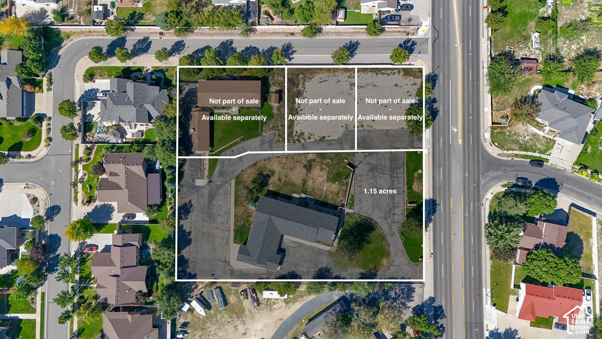 1.15-acre parcel featuring an expansive asphalt surface, mature perimeter trees, and a multi-section structure with a dark-tone gabled roof