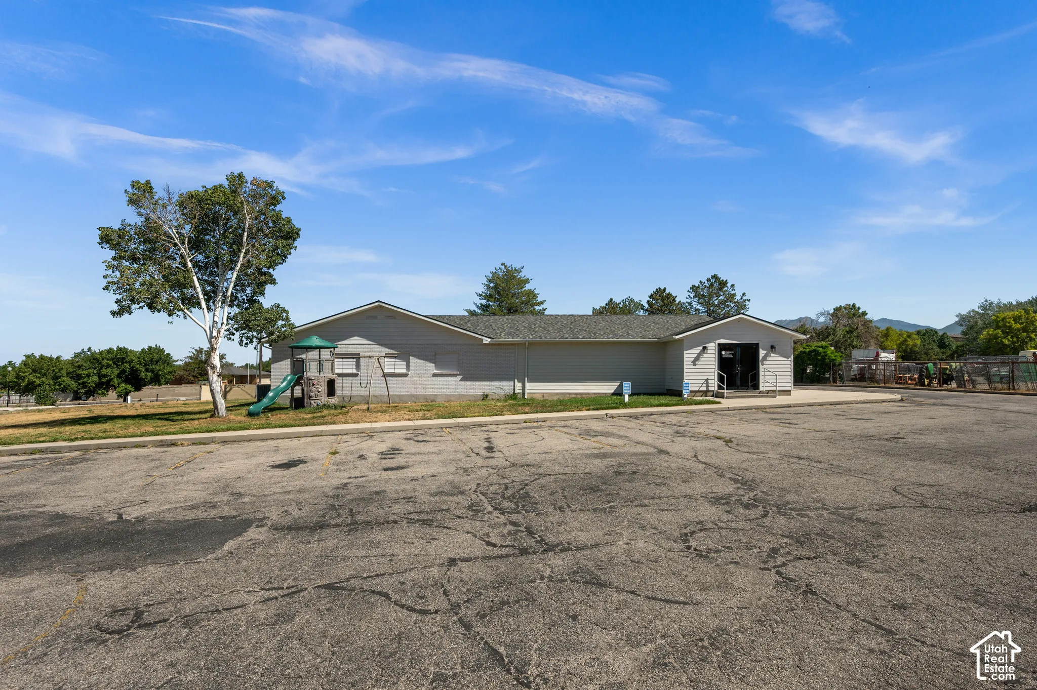 Exterior building with light gray siding, dark shingle roof, and a prominent entry