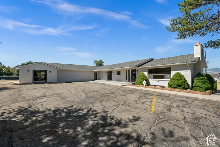 Expansive paved lot, white exterior, covered entryway, double glass doors, and a brick chimney