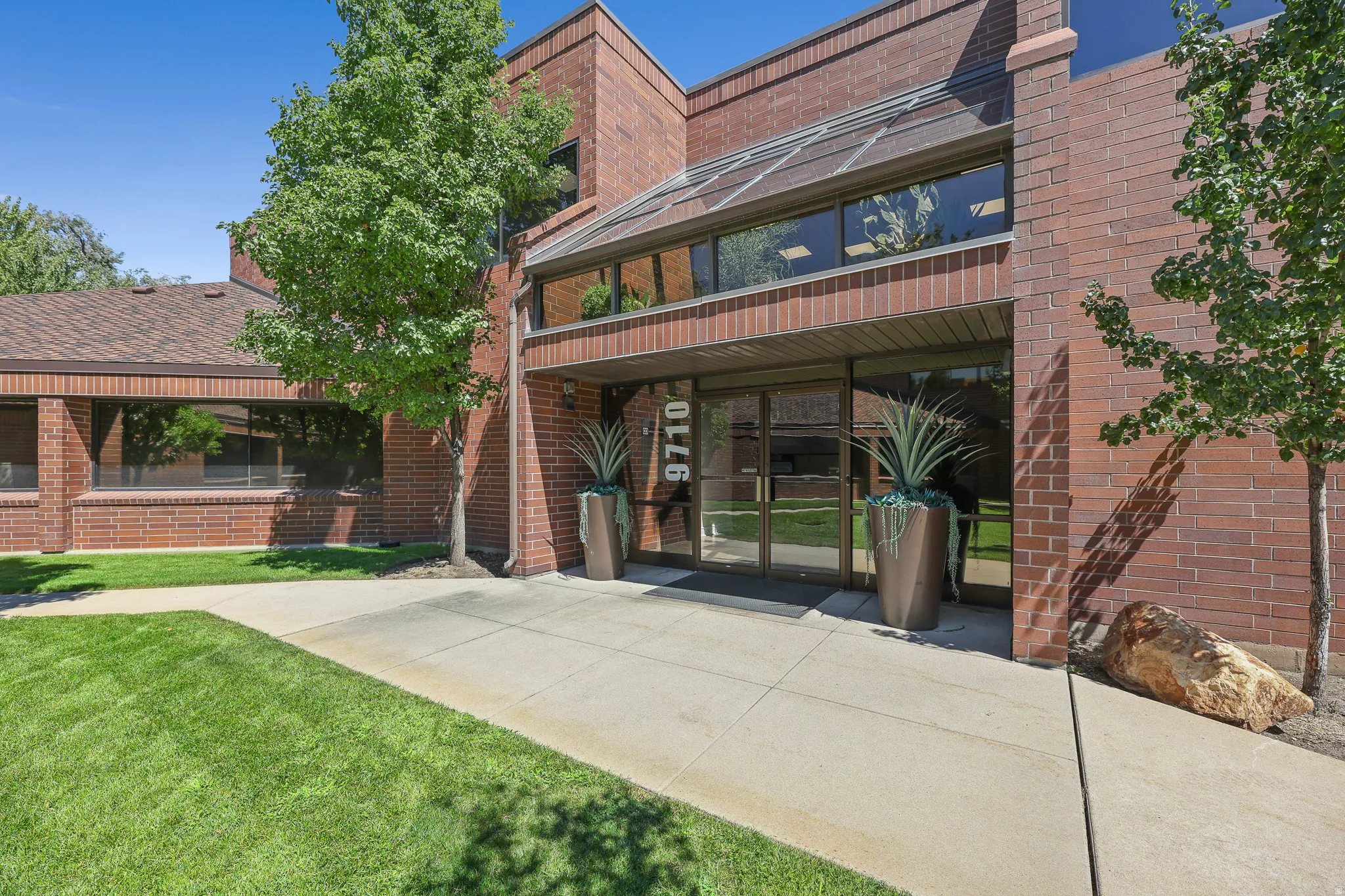 Brick exterior with a glass-enclosed entry, expansive windows, and a concrete walkway