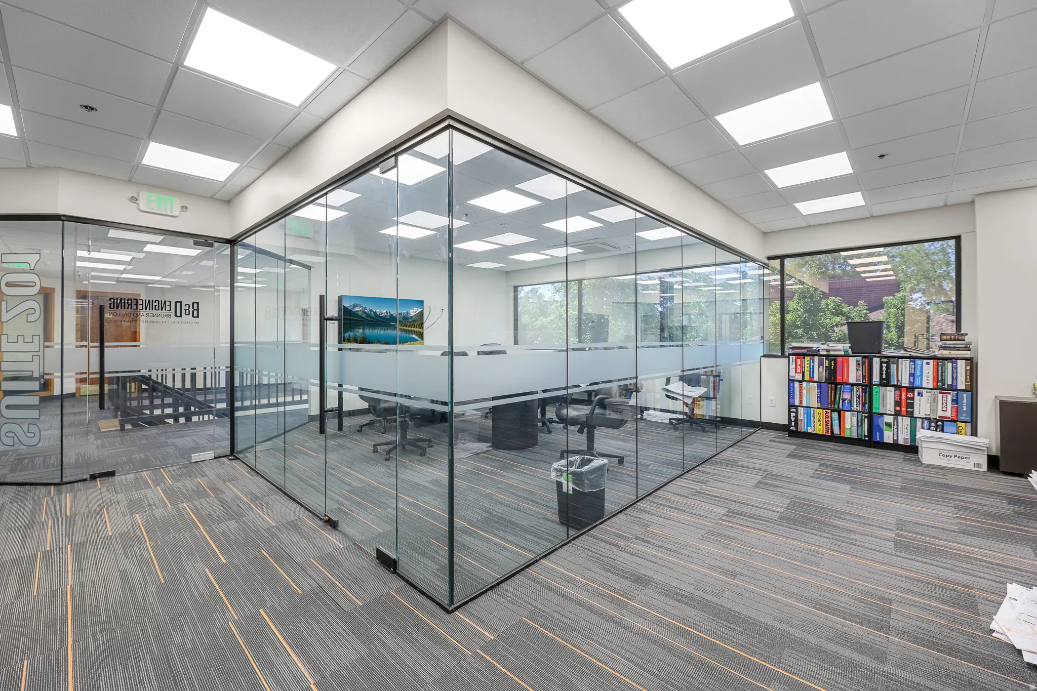 Glass-enclosed conference room with frosted privacy banding, suspended ceiling with recessed lighting, and carpet flooring