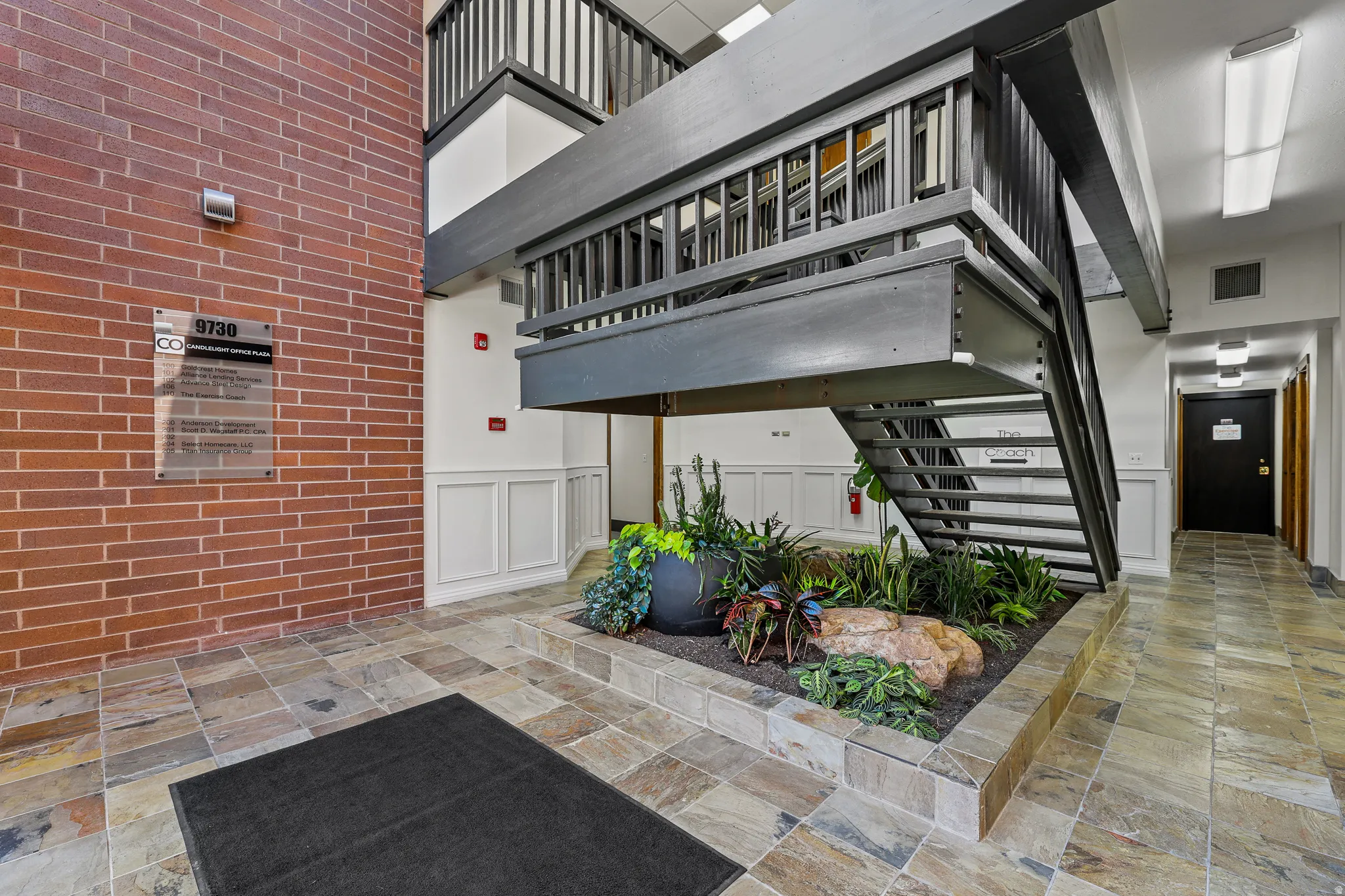 Brick wall detailing, multi-level staircase, wainscoting, tiled flooring, and a built-in planter