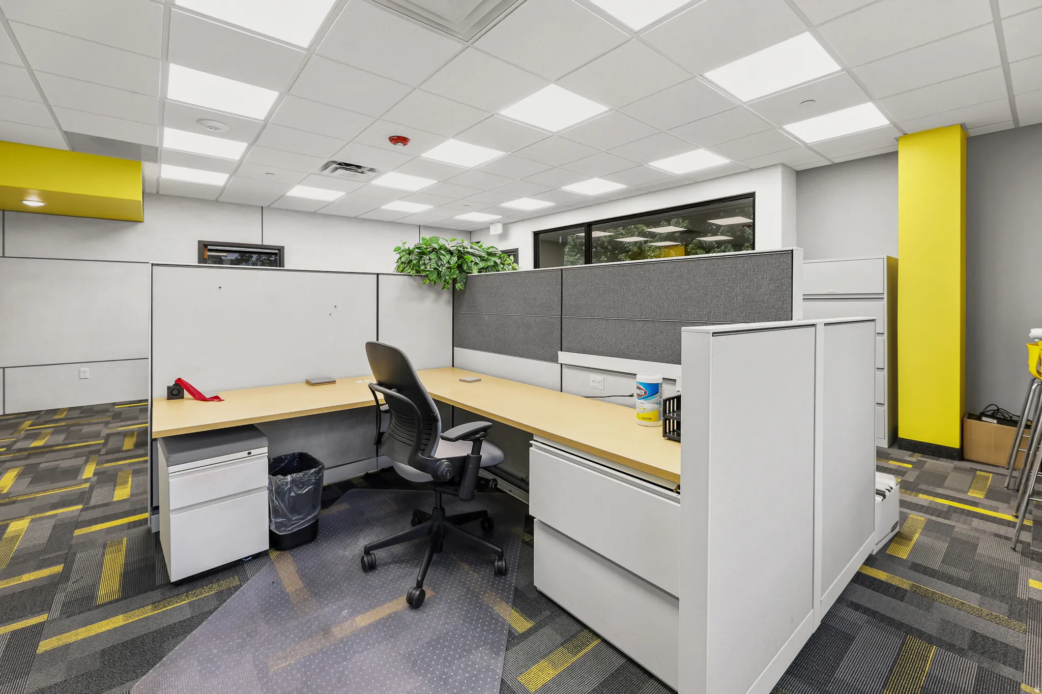 Modular workstation with light wood-finish desktops, gray fabric panels, and integrated storage