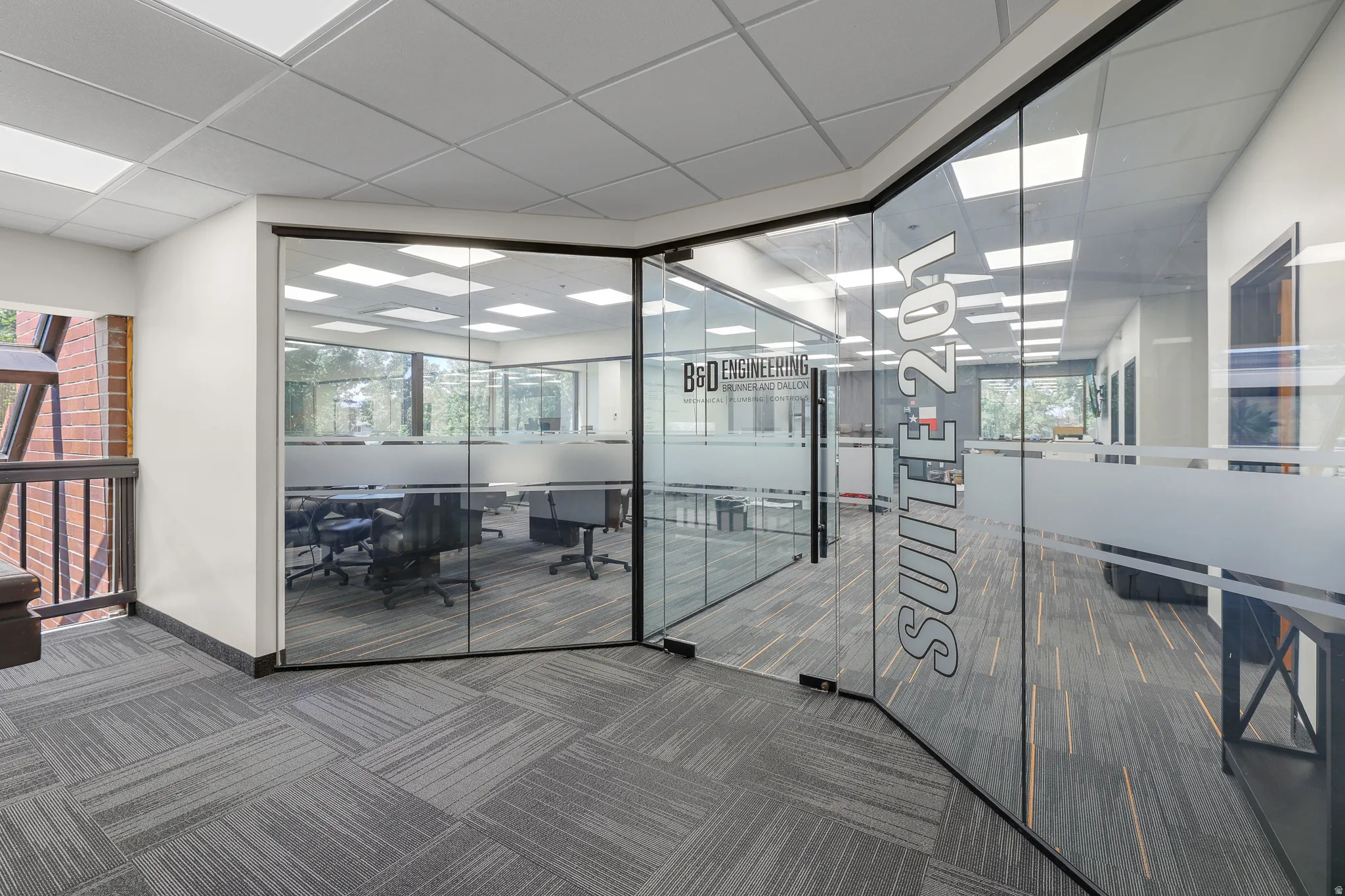 Glass-enclosed office space featuring a drop ceiling, recessed lighting, and patterned carpet flooring