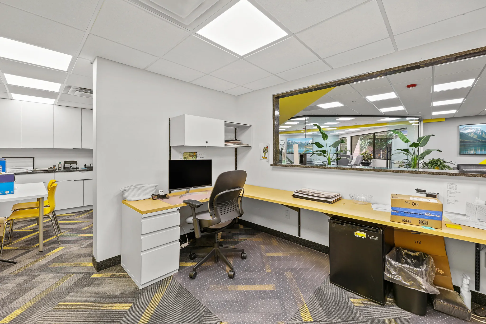 Modular office space featuring built-in cabinetry, overhead lighting, and a large interior window