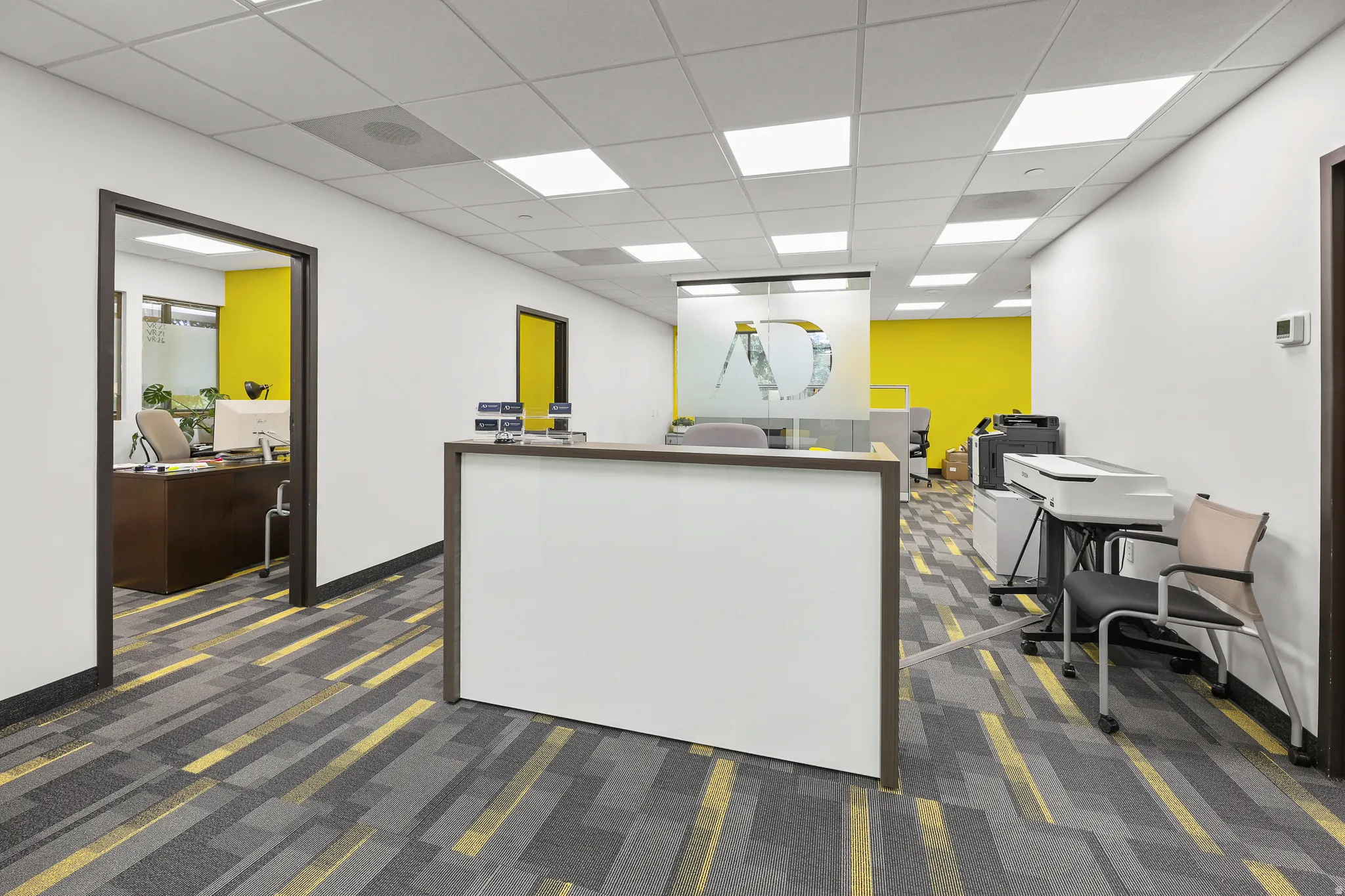 Reception area featuring a white counter, patterned carpet flooring, and recessed ceiling lighting