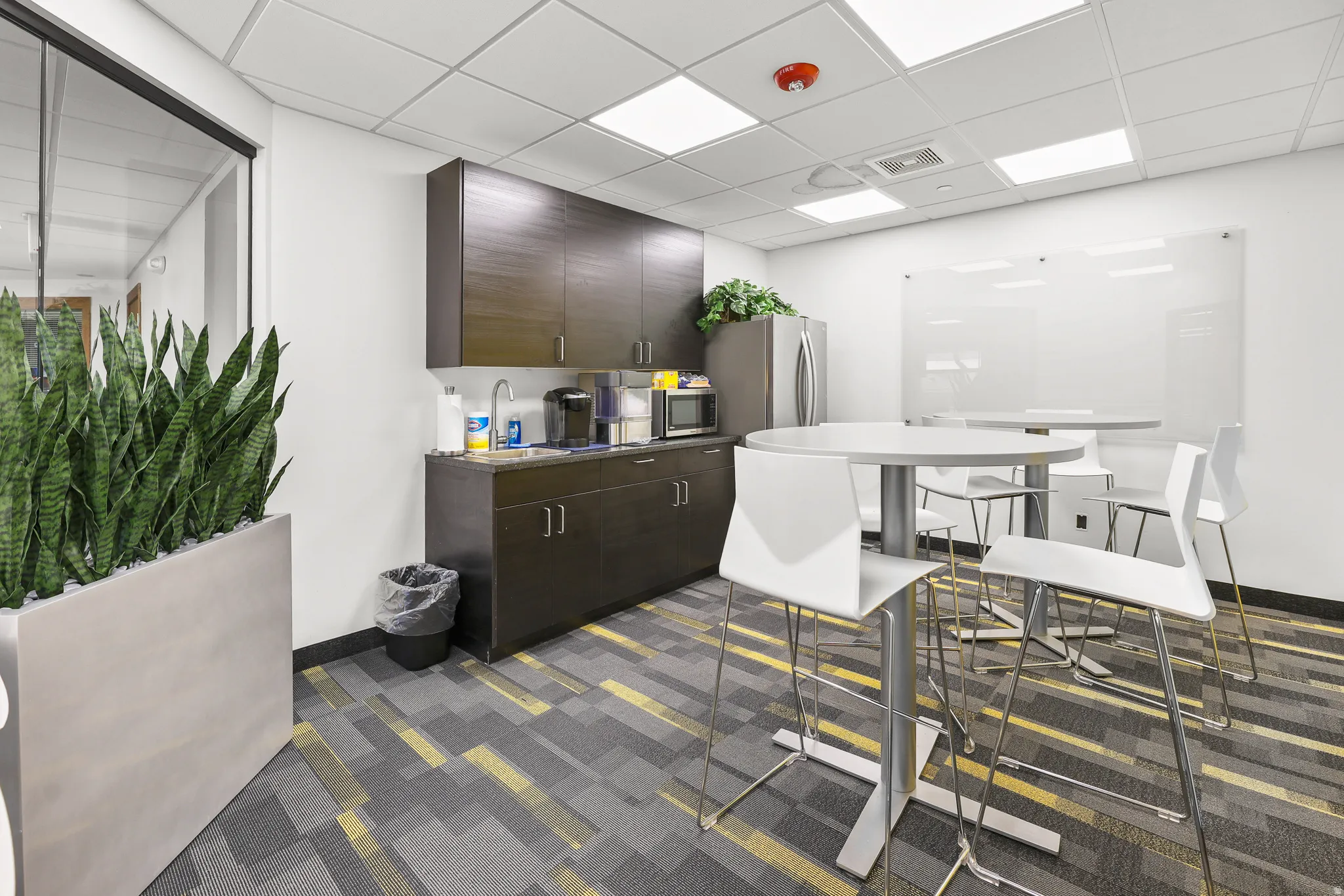 Kitchenette featuring dark wood-finish cabinetry, a stainless steel refrigerator, and a built-in sink