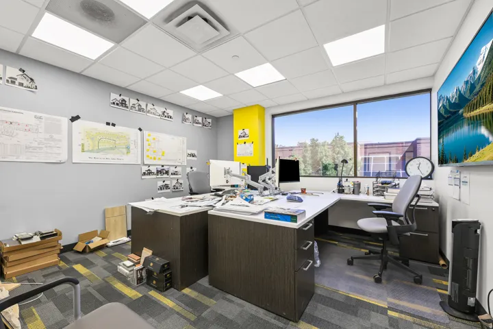 Expansive window line, modular ceiling tiles with recessed lighting, patterned carpet flooring, and a feature wall