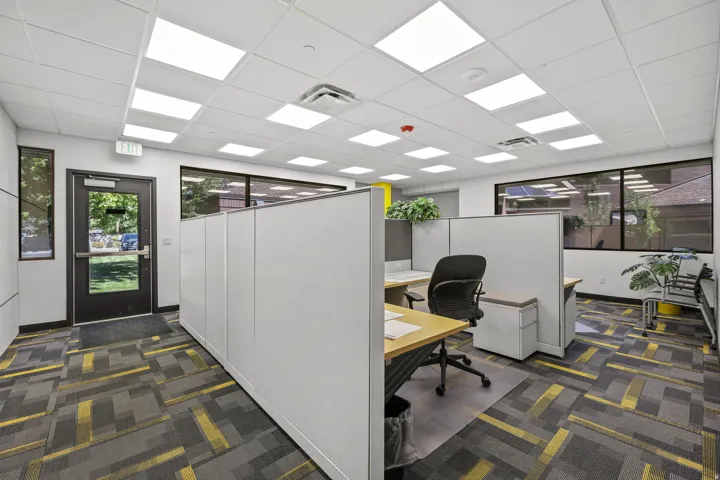 Commercial space featuring a drop ceiling with recessed lighting, full-length windows, a glass-panel entry door, and patterned carpet flooring