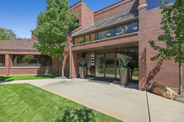 Brick exterior with a glass-enclosed entry, expansive windows, and a concrete walkway
