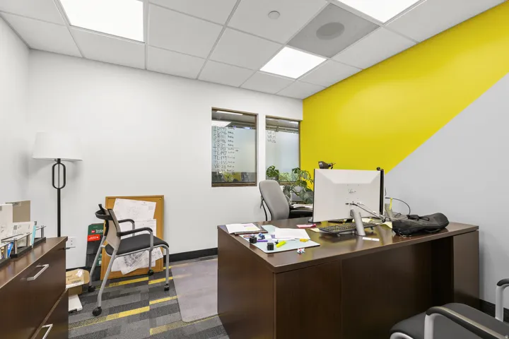 Interior office space featuring a drop ceiling with recessed lighting, two windows, and a carpeted floor