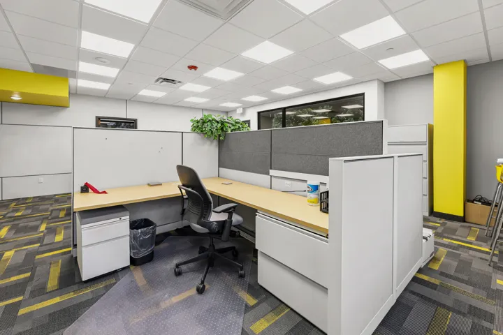 Modular workstation with light wood-finish desktops, gray fabric panels, and integrated storage