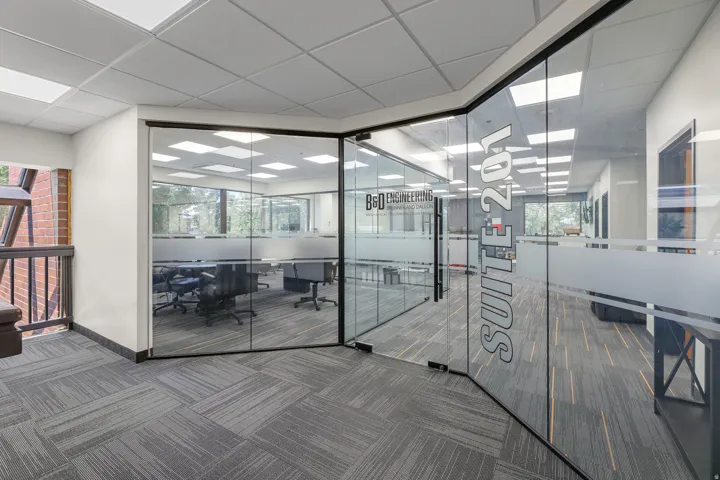 Glass-enclosed office space featuring a drop ceiling, recessed lighting, and patterned carpet flooring