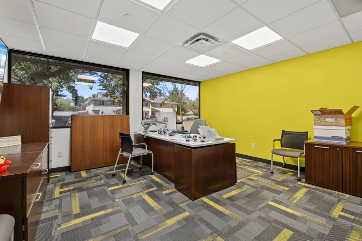 Expansive windows, suspended ceiling with integrated lighting, wood-finish built-in cabinetry, and patterned carpet