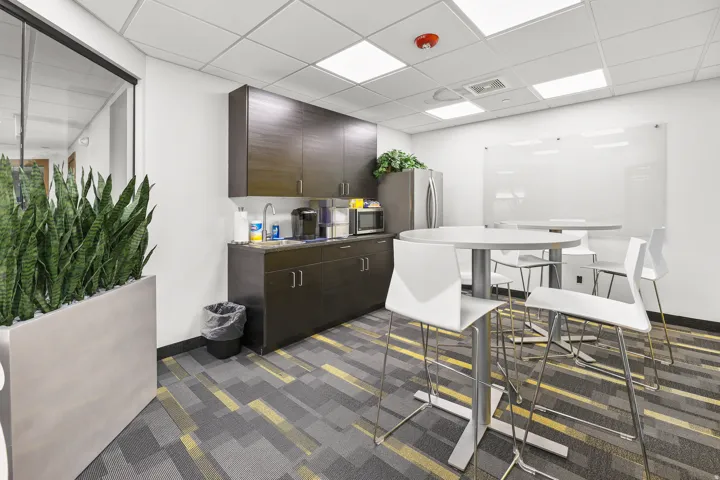 Kitchenette featuring dark wood-finish cabinetry, a stainless steel refrigerator, and a built-in sink