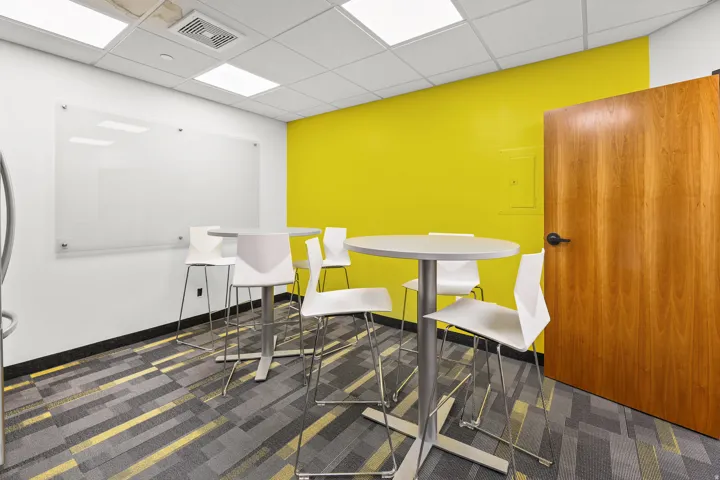 Accent wall, wood-finish door, patterned carpet flooring, suspended acoustic ceiling, and ceiling-mounted lighting
