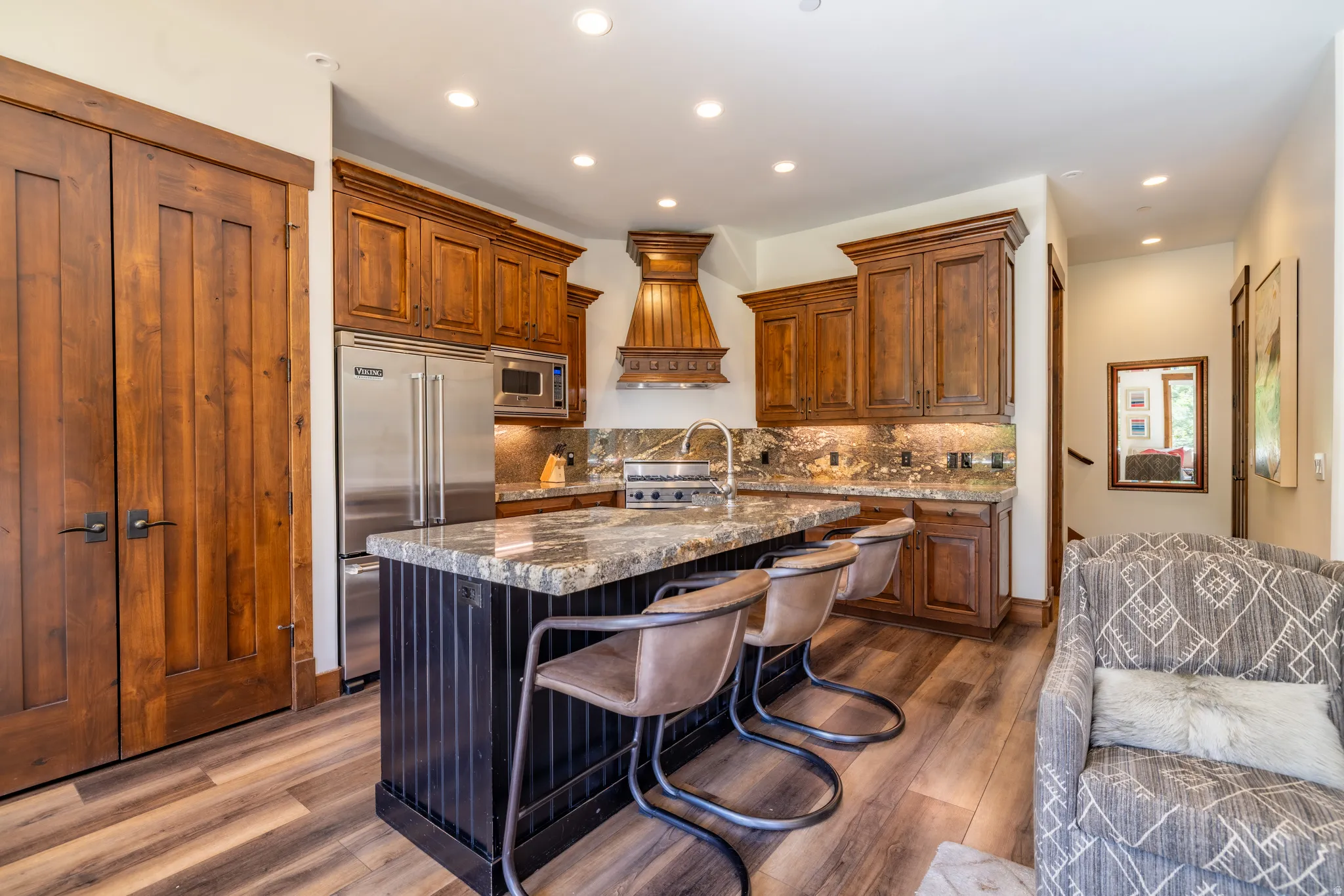 Gourmet kitchen with wood cabinetry, stainless steel appliances, a center island with bar seating, and stone countertops