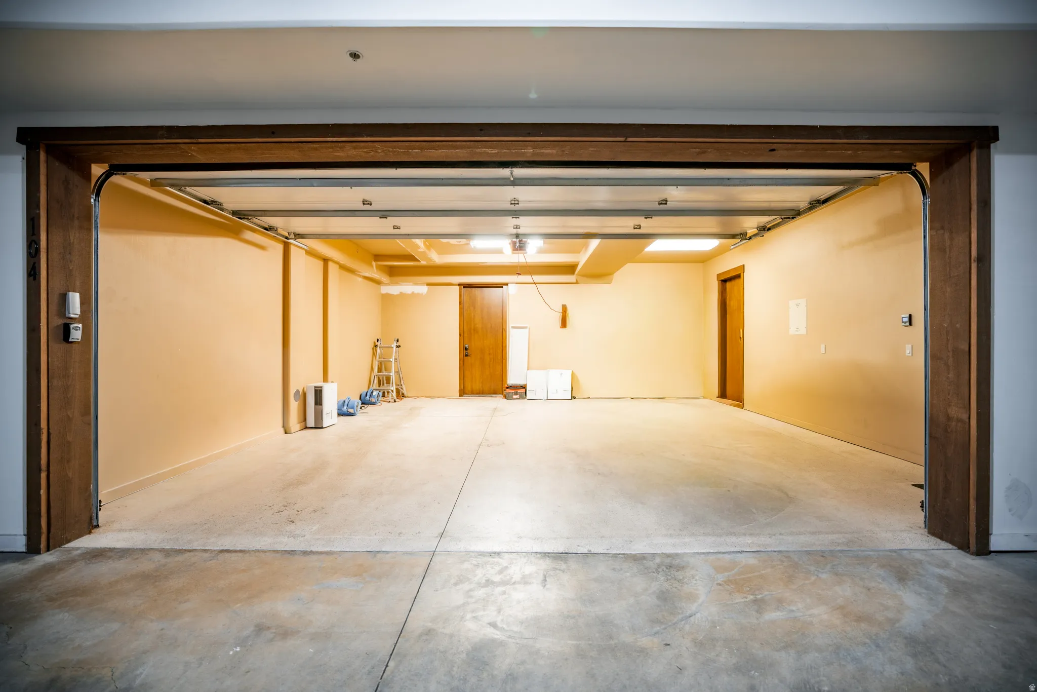 Spacious garage with concrete flooring, wood door frames, and overhead lighting