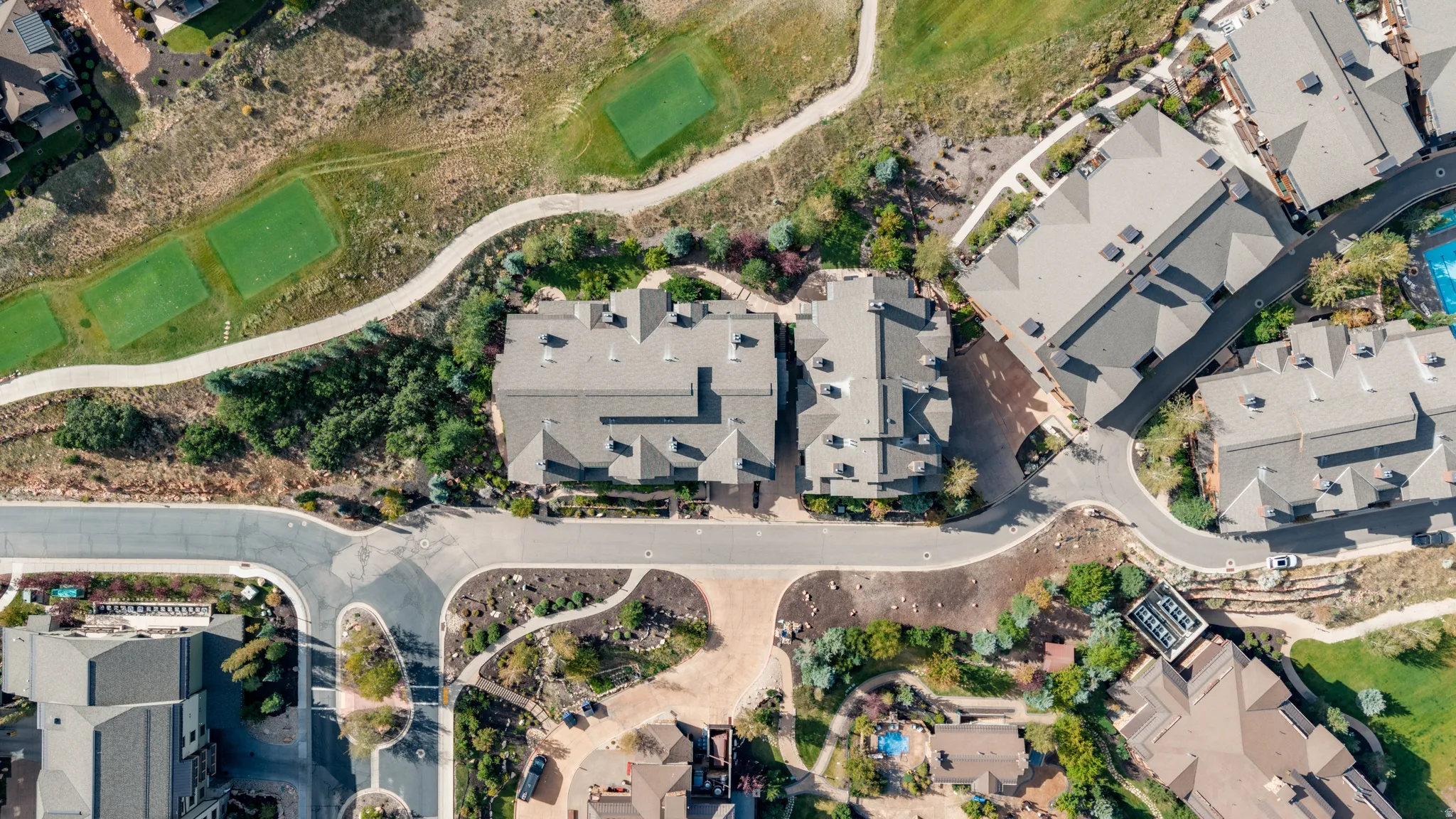 Aerial perspective showcasing residential structures with multiple rooftops, paved roadways, and landscaped grounds