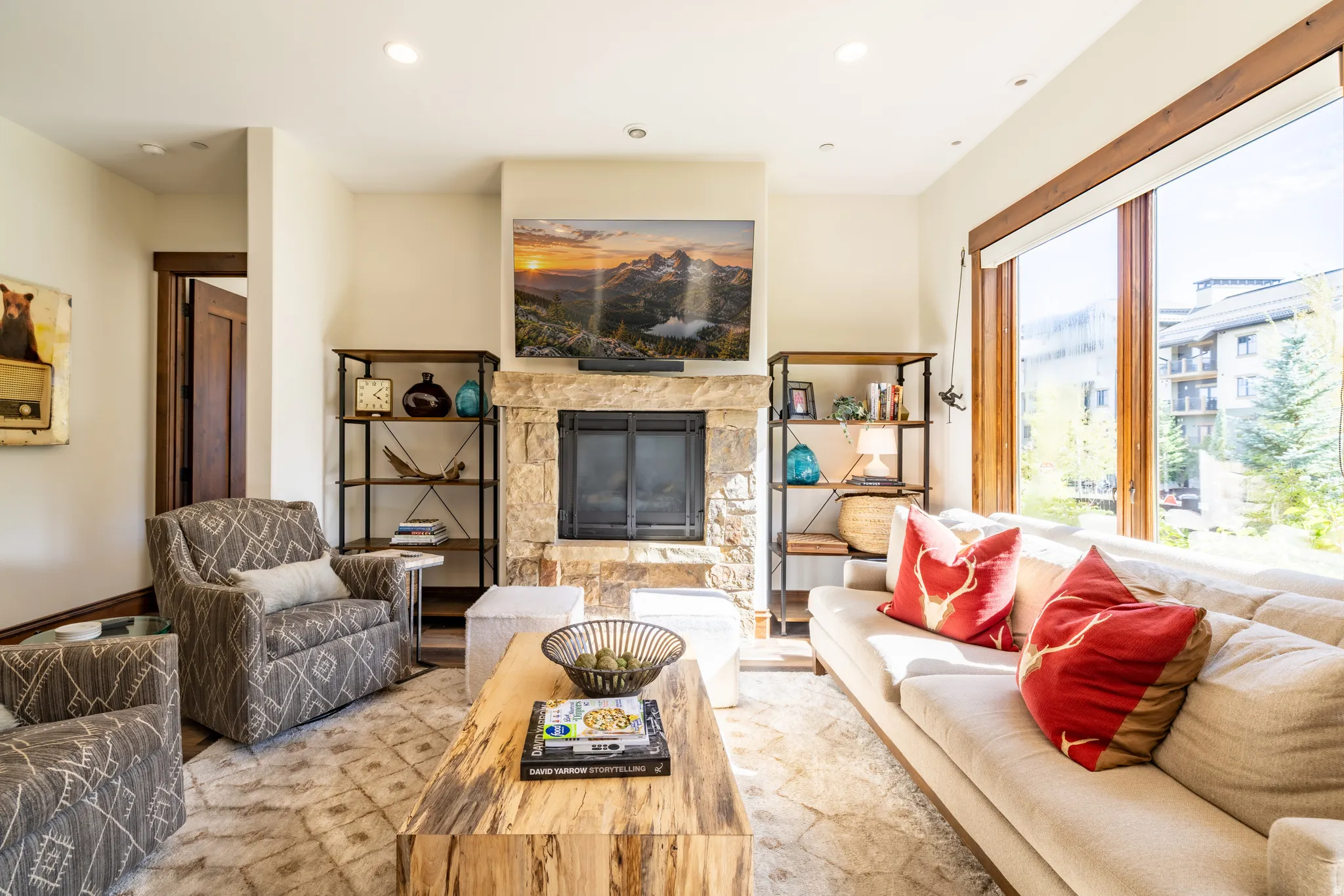 Stone-clad fireplace with a built-in firebox, recessed lighting, expansive wood-framed windows, and custom built-in shelving