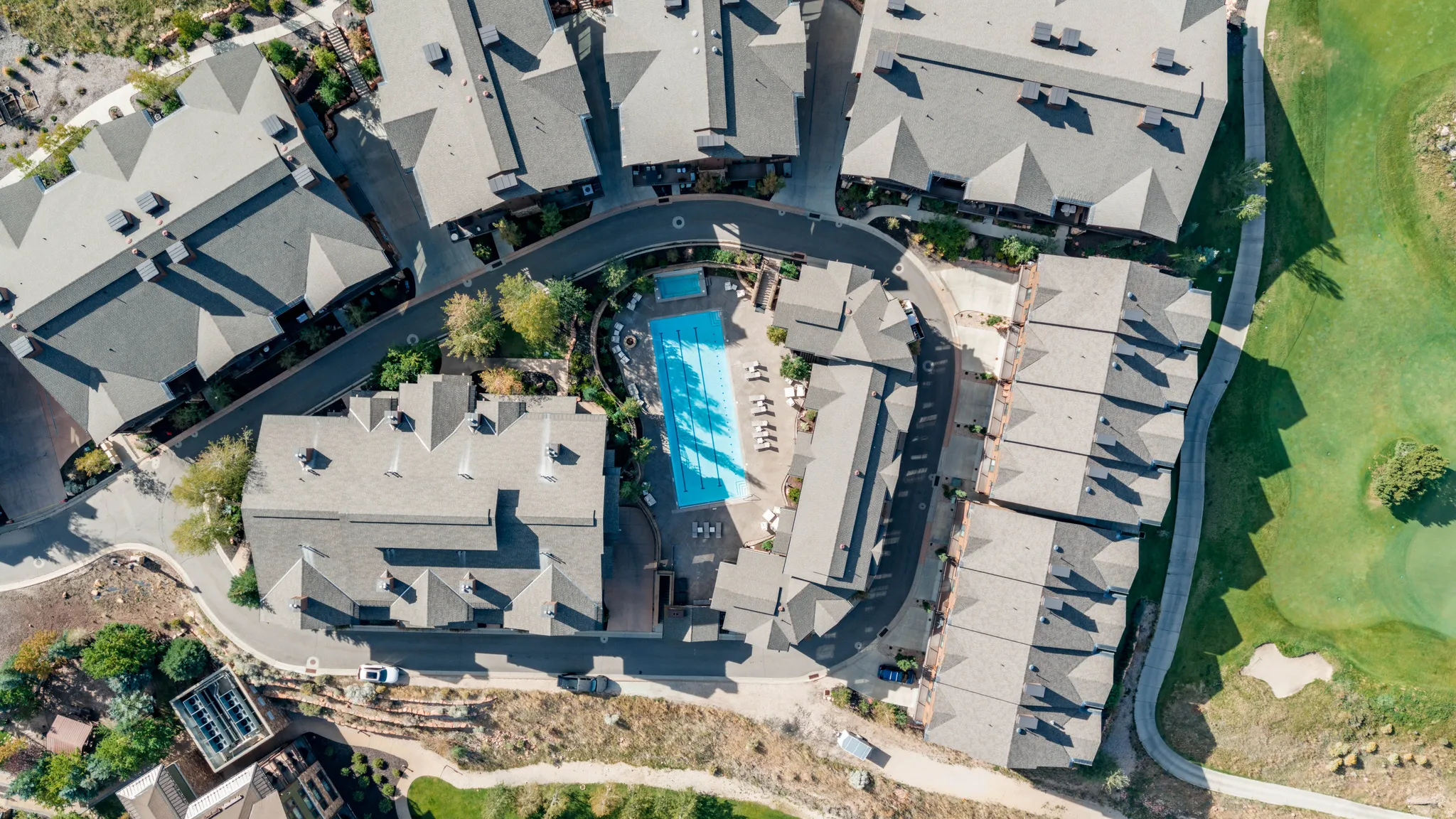 Community with multiple residential buildings, a central swimming pool, and adjacent golf course