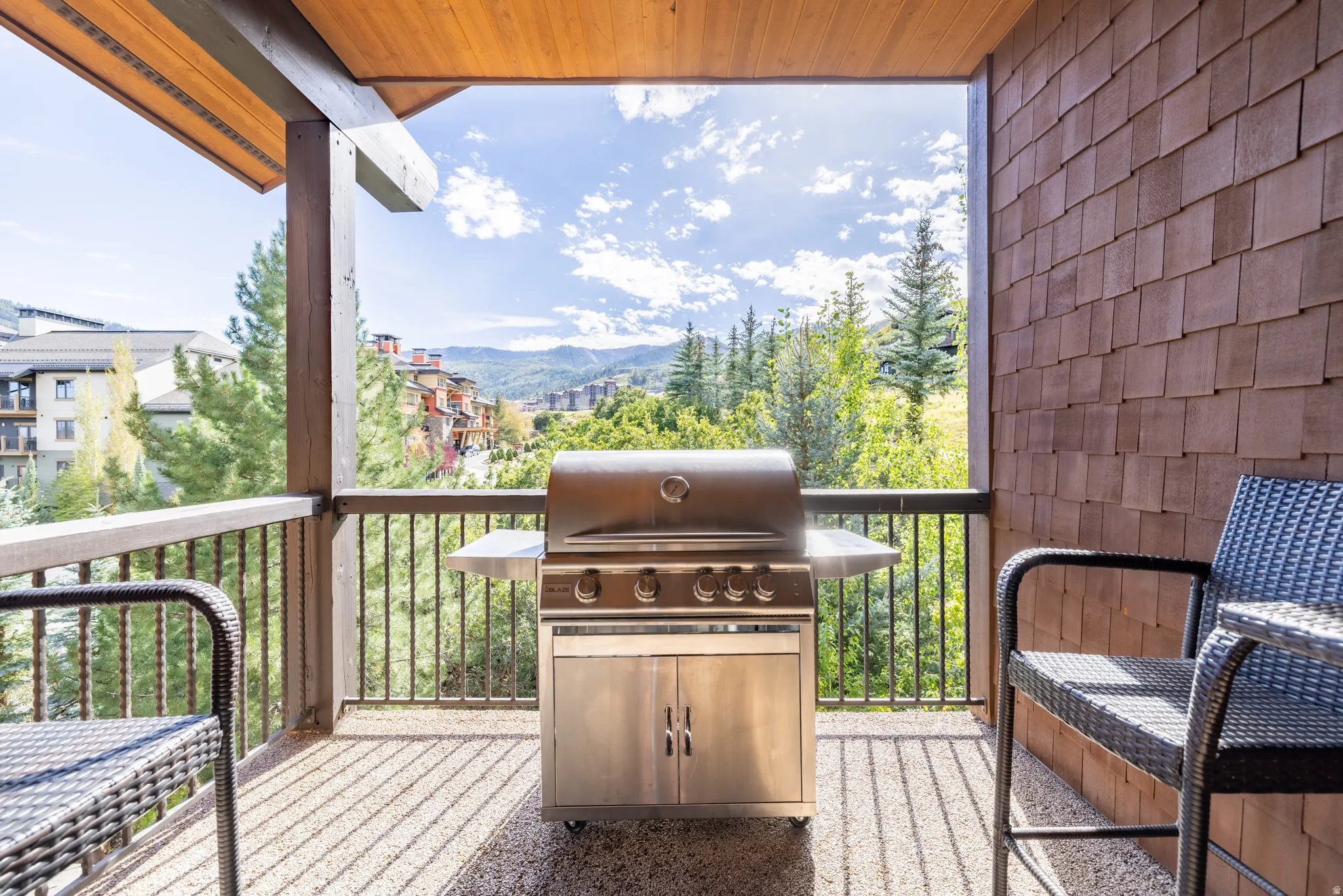 Covered outdoor patio with exposed wood ceiling beams, textured flooring, and a stainless steel built-in grill
