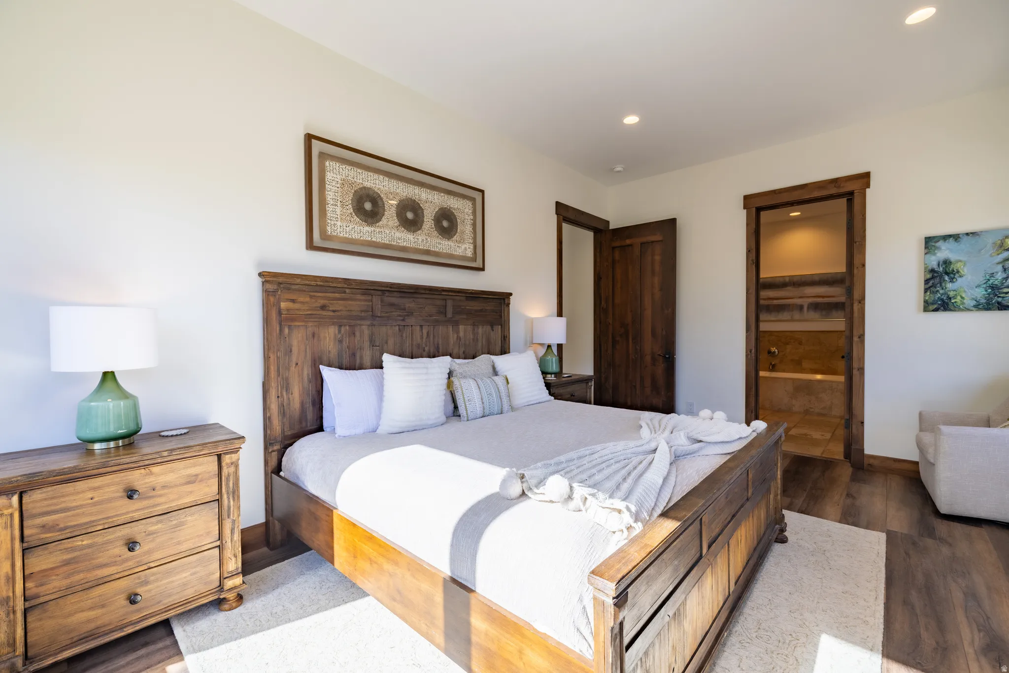 Wood-finish flooring, recessed ceiling lights, solid wood doors, and a wood-framed entrance to an adjacent room