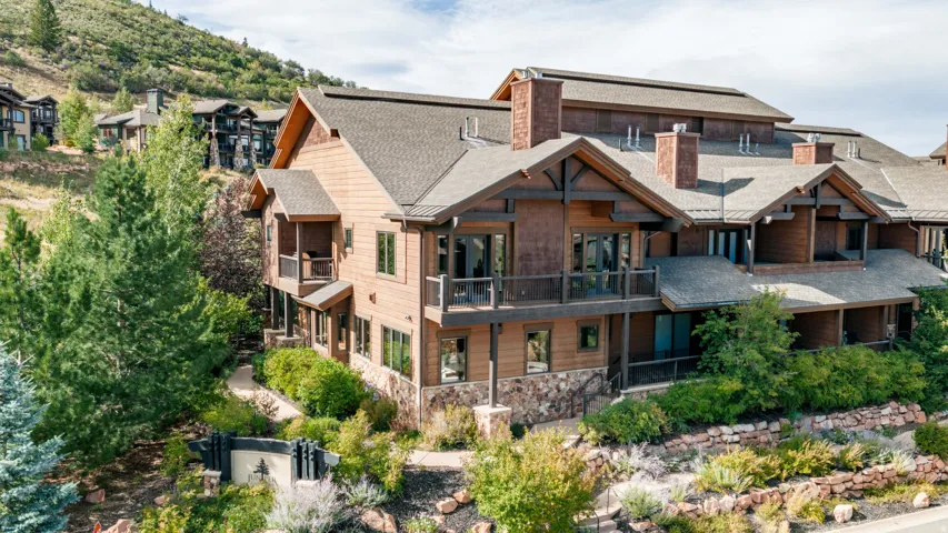 Multi-level exterior featuring wood siding, stone accents, multiple balconies, and lush landscaping