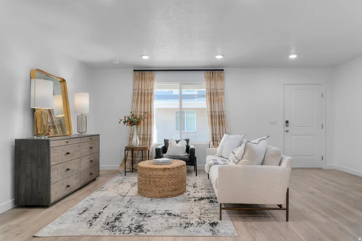 Recessed lighting, wood-finish flooring, white paneled door, and a prominent window