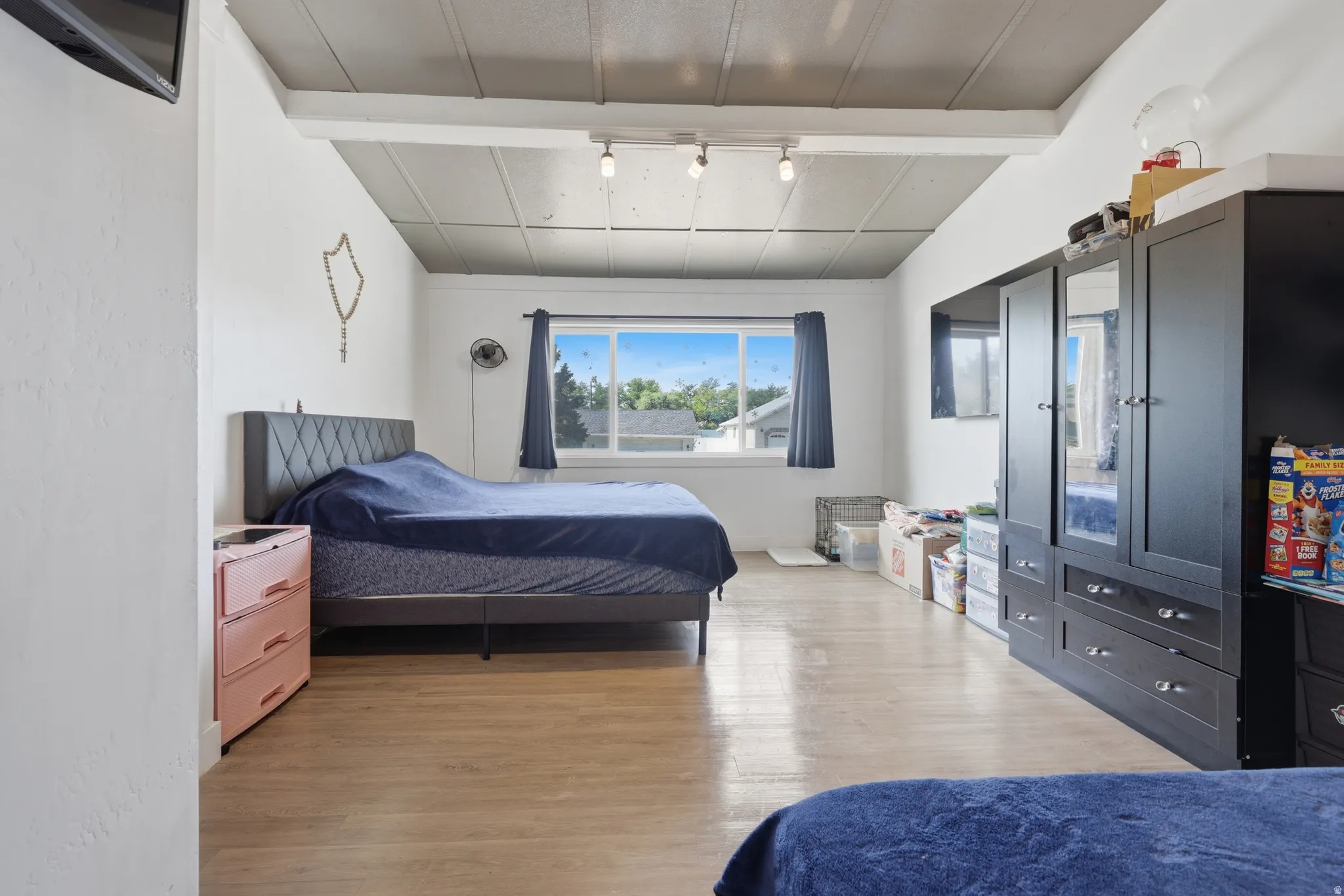 Spacious room featuring wood-finish flooring, white walls, and a window providing natural light