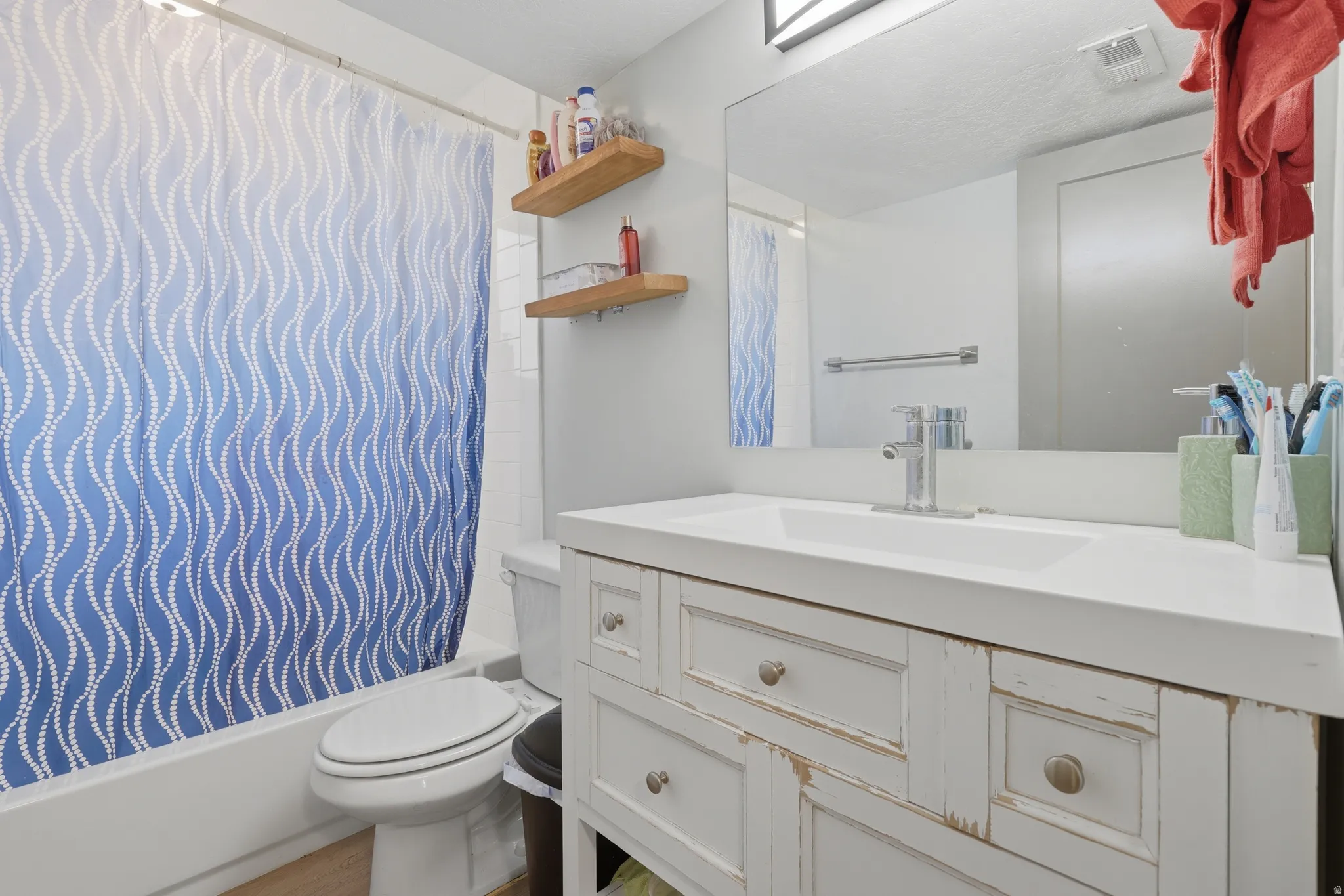 White vanity with a single basin sink, chrome faucet, and rectangular mirror
