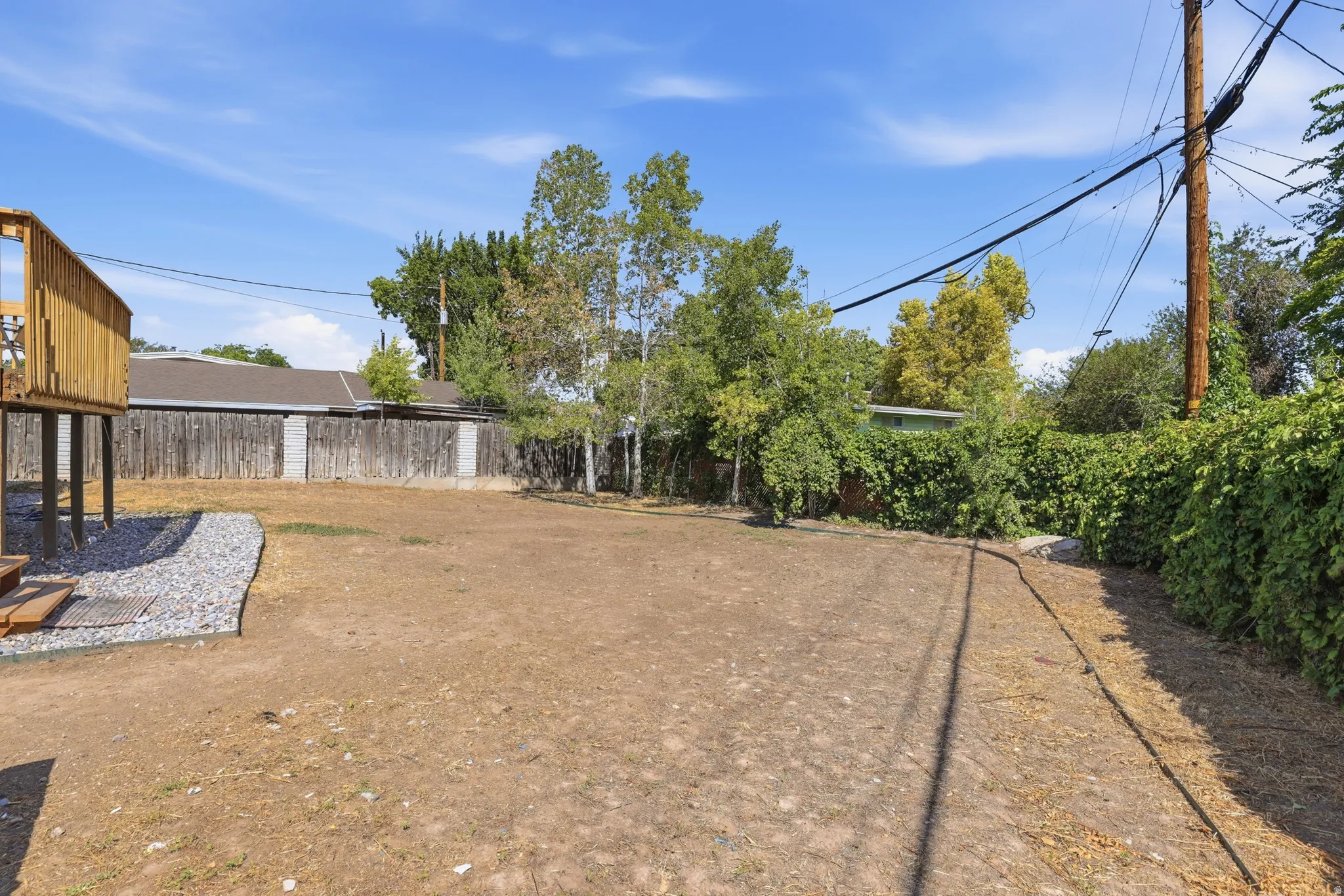 Expansive backyard featuring a natural ground surface, mature perimeter trees, and a wooden elevated structure